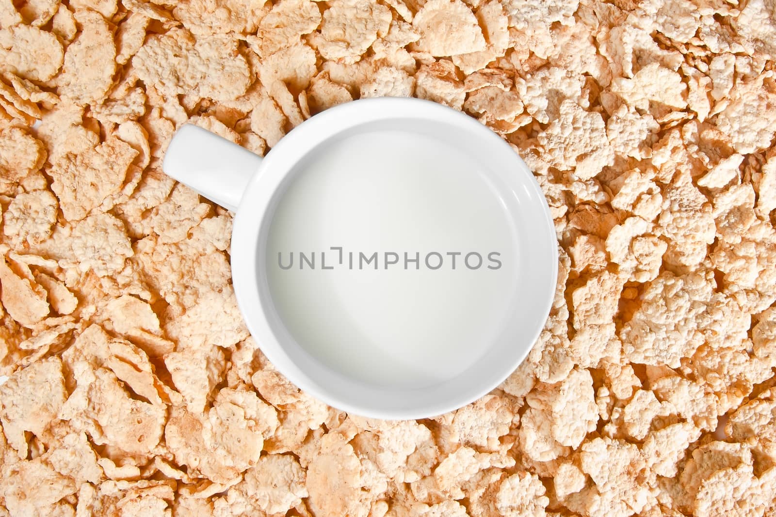 top of view of cup of milk on corn flakes background, breakfast concept