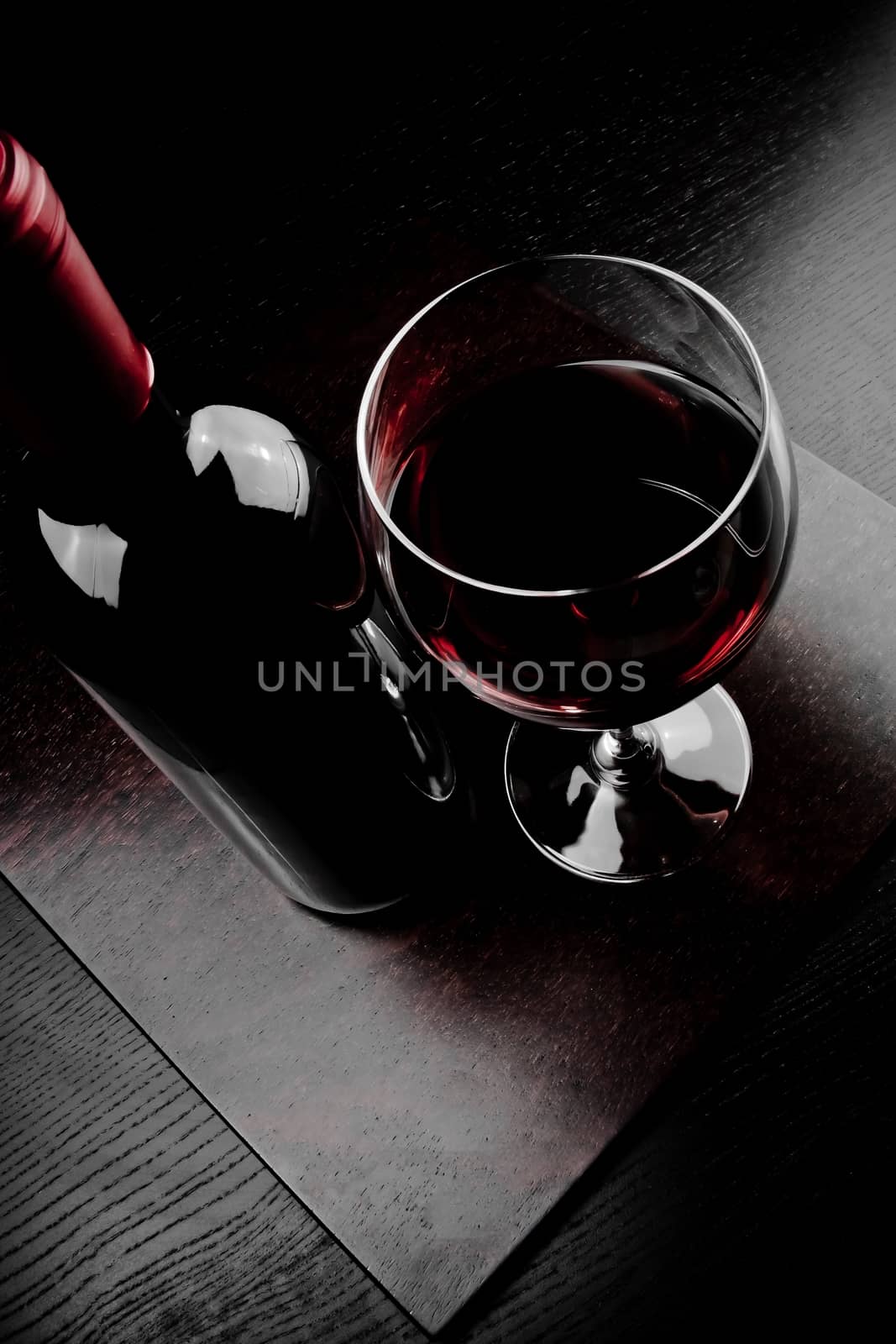 red wine glass near bottle on old wood table