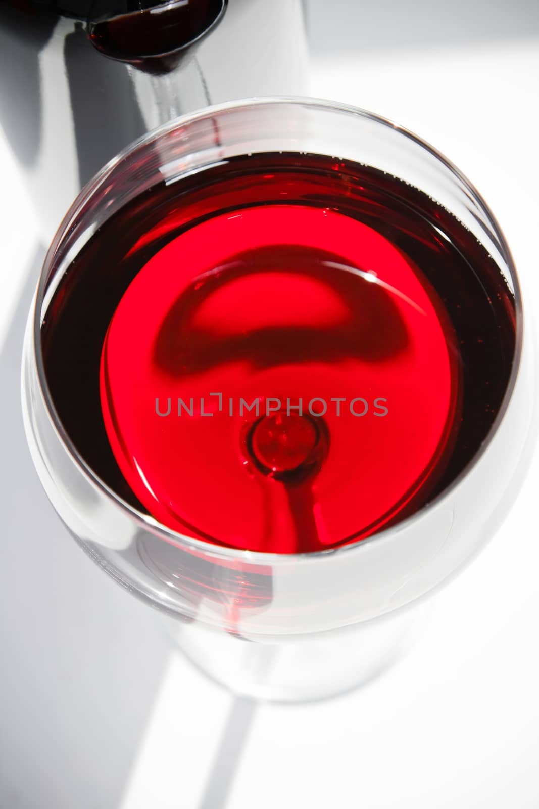 top of view of red wine glass near a bottle under daily light by donfiore