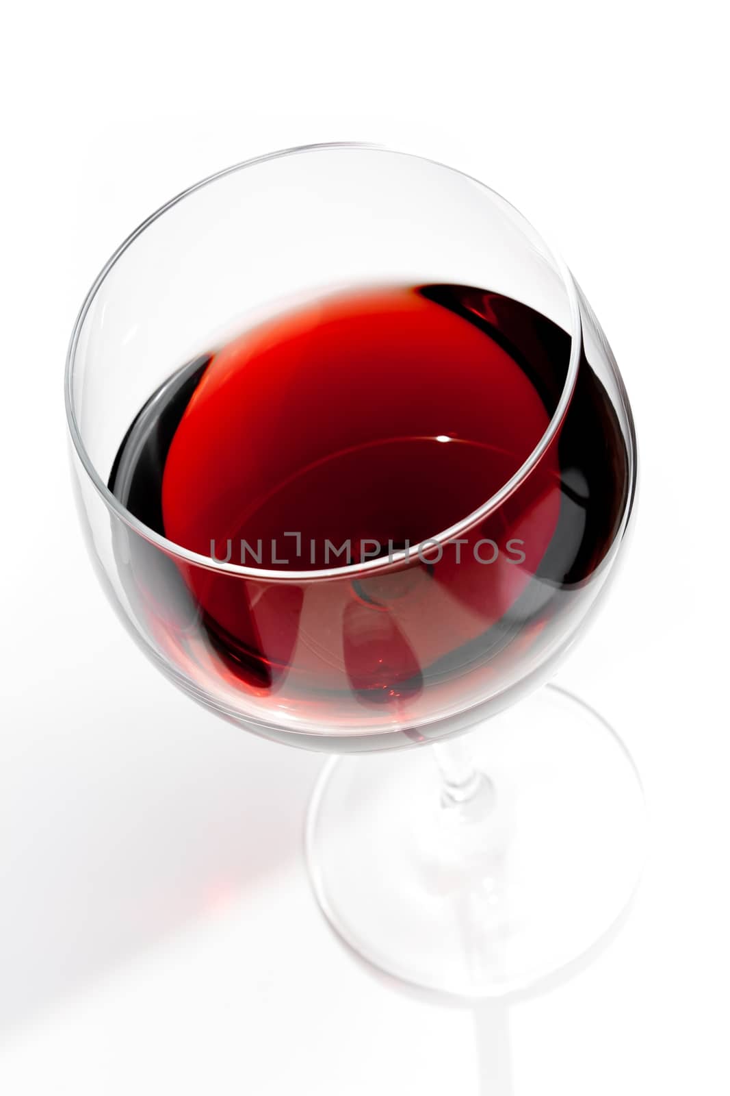 top of view of red wine glass under daily light on white table