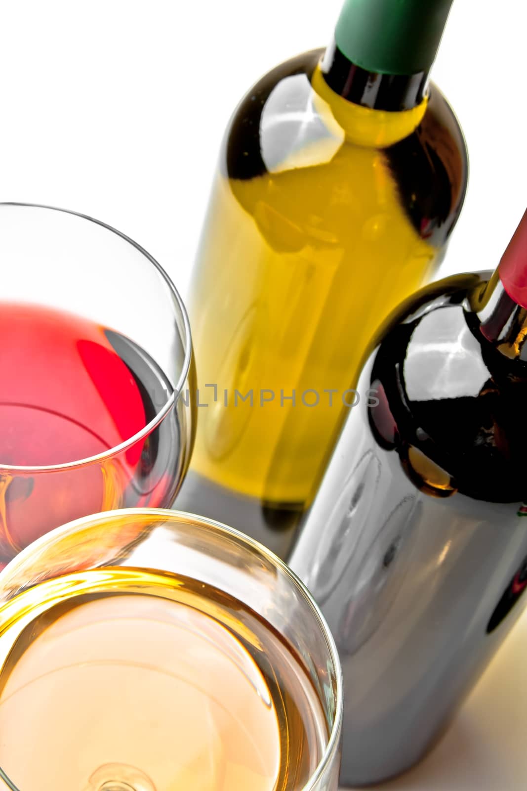red and white wine glasses near wine bottles on white background