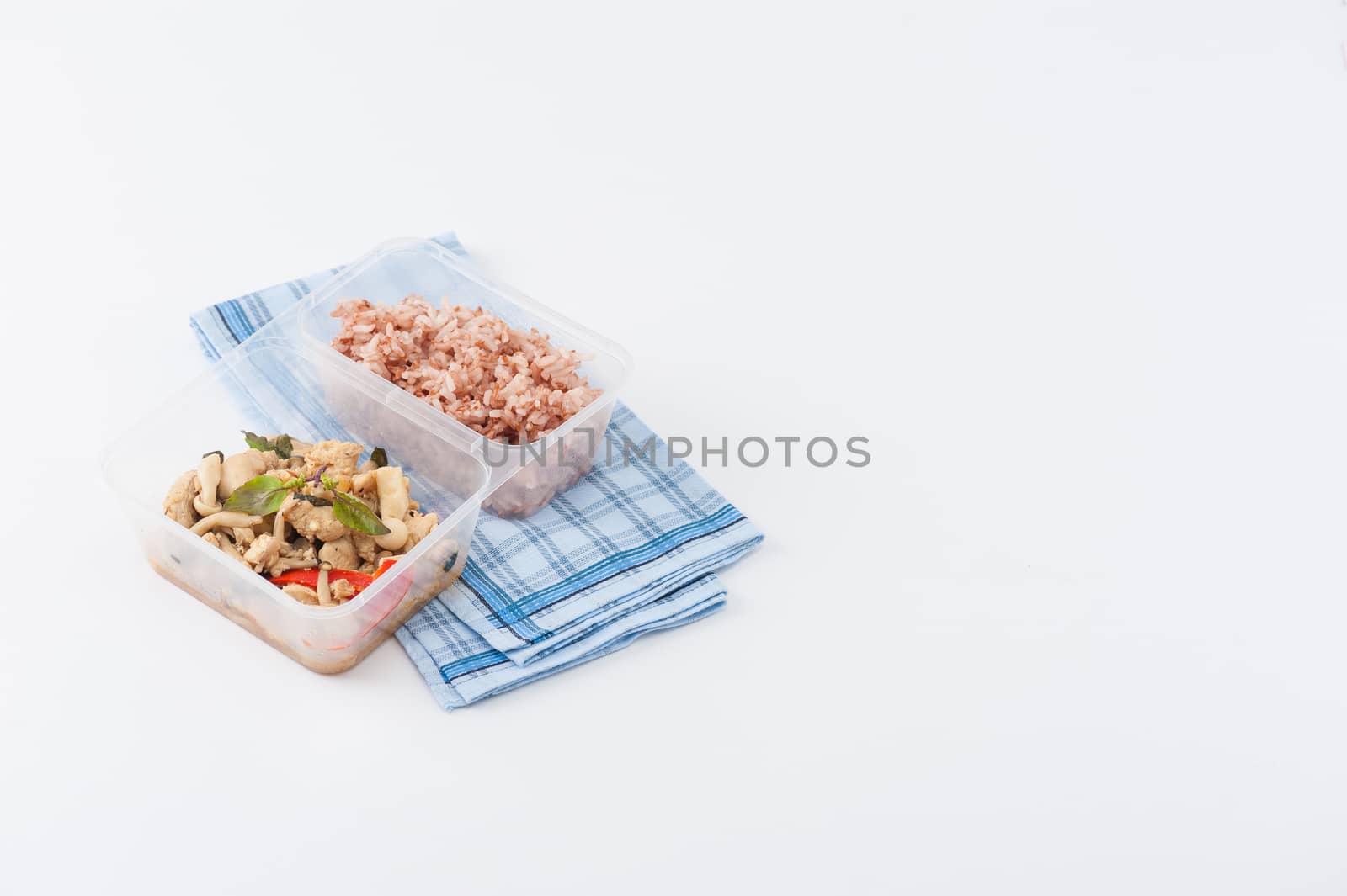 Stir freid basil with chicken breast and Termitomyces cooked by clean food concept with brown rice in lunch box isolated on white background with clipping path