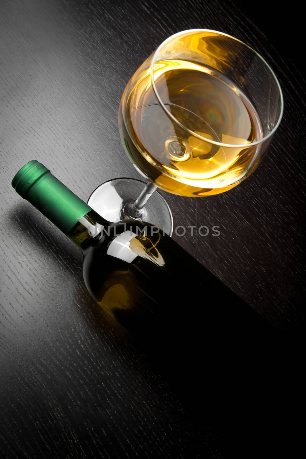 top of view of white wine glass near bottle on old wood table