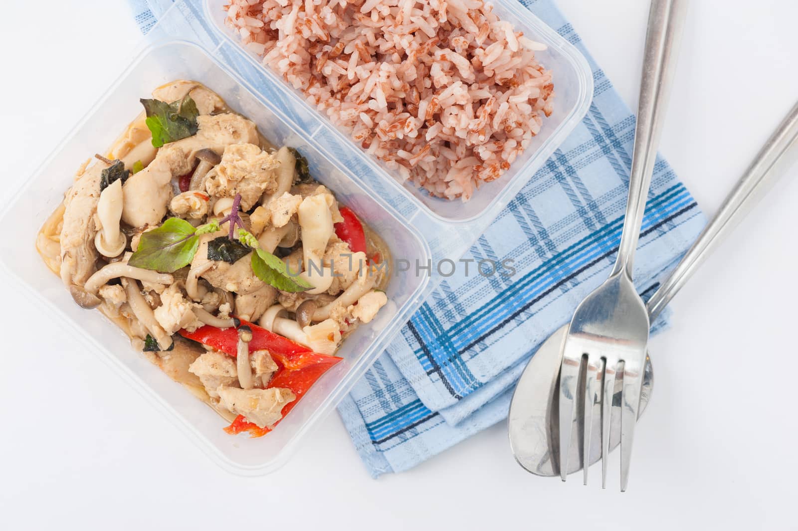 Stir freid basil with chicken breast and Termitomyces cooked by clean food concept with brown rice in lunch box on white table