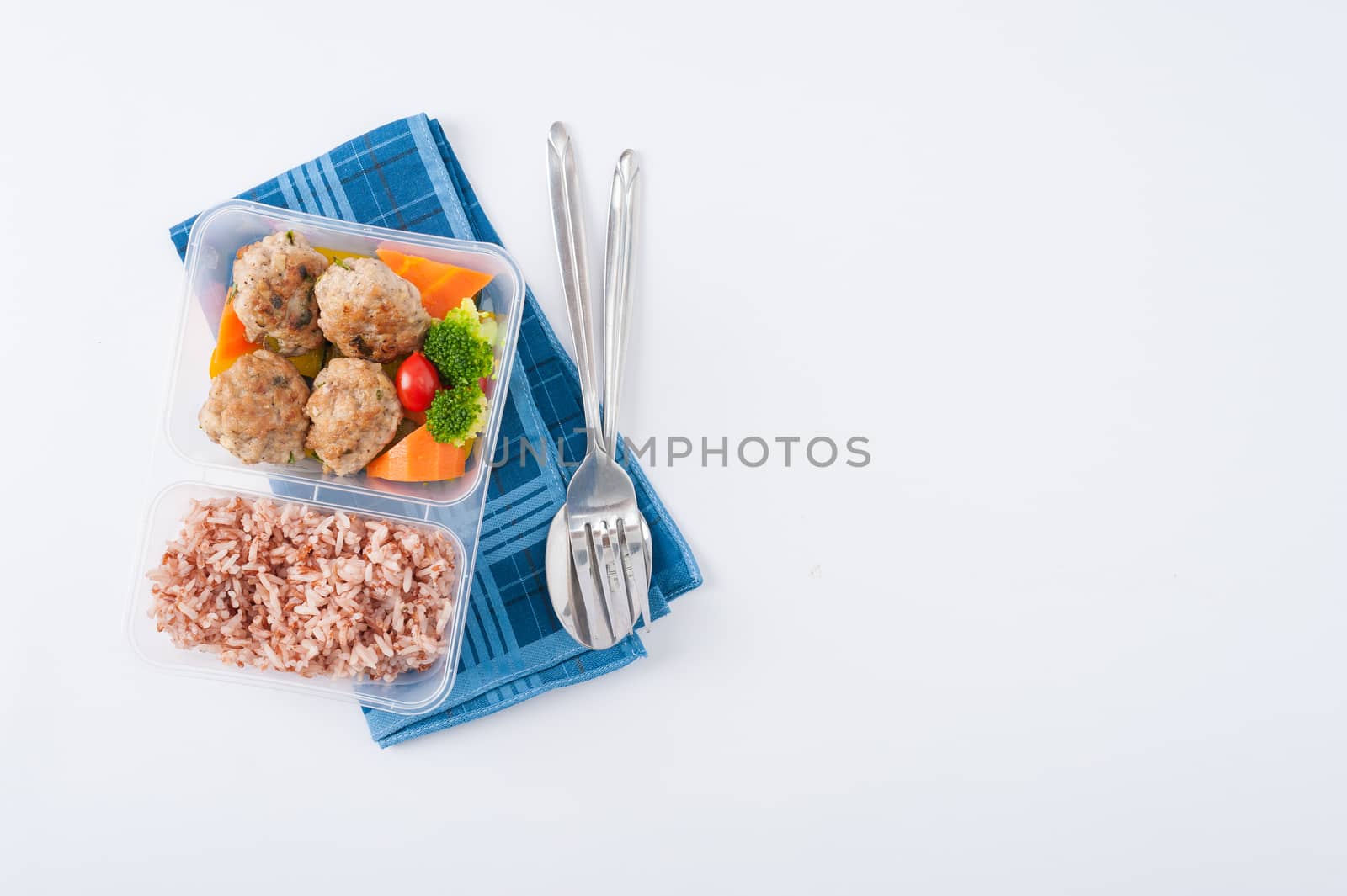Thai style fried pork ball cooked by clean food concept with vegetables and brown rice in lunch box on white table