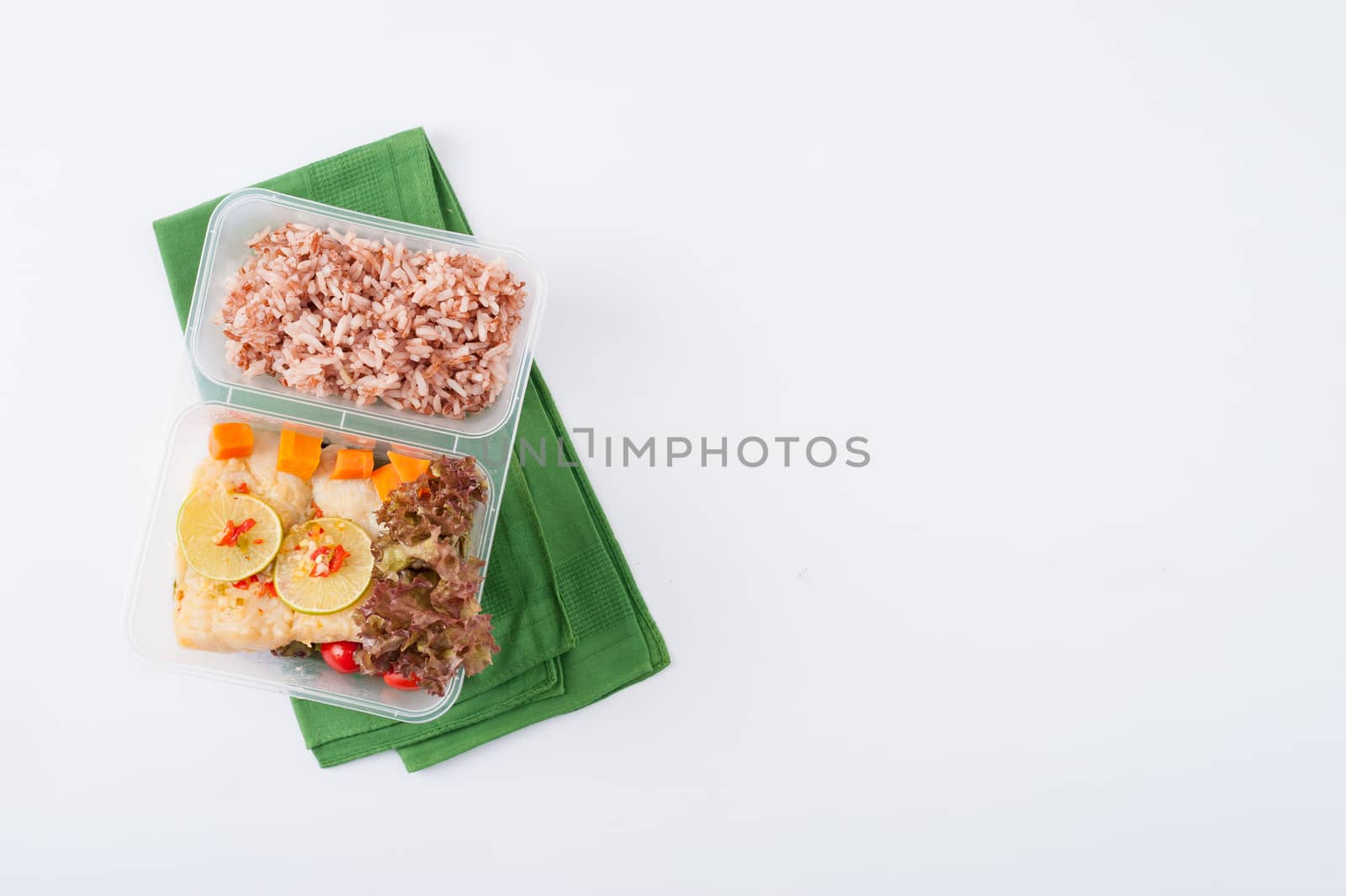 Thai style steamed fish in spicy lemon sauce cooked by clean food concept with vegetables and brown rice in lunch box on white table