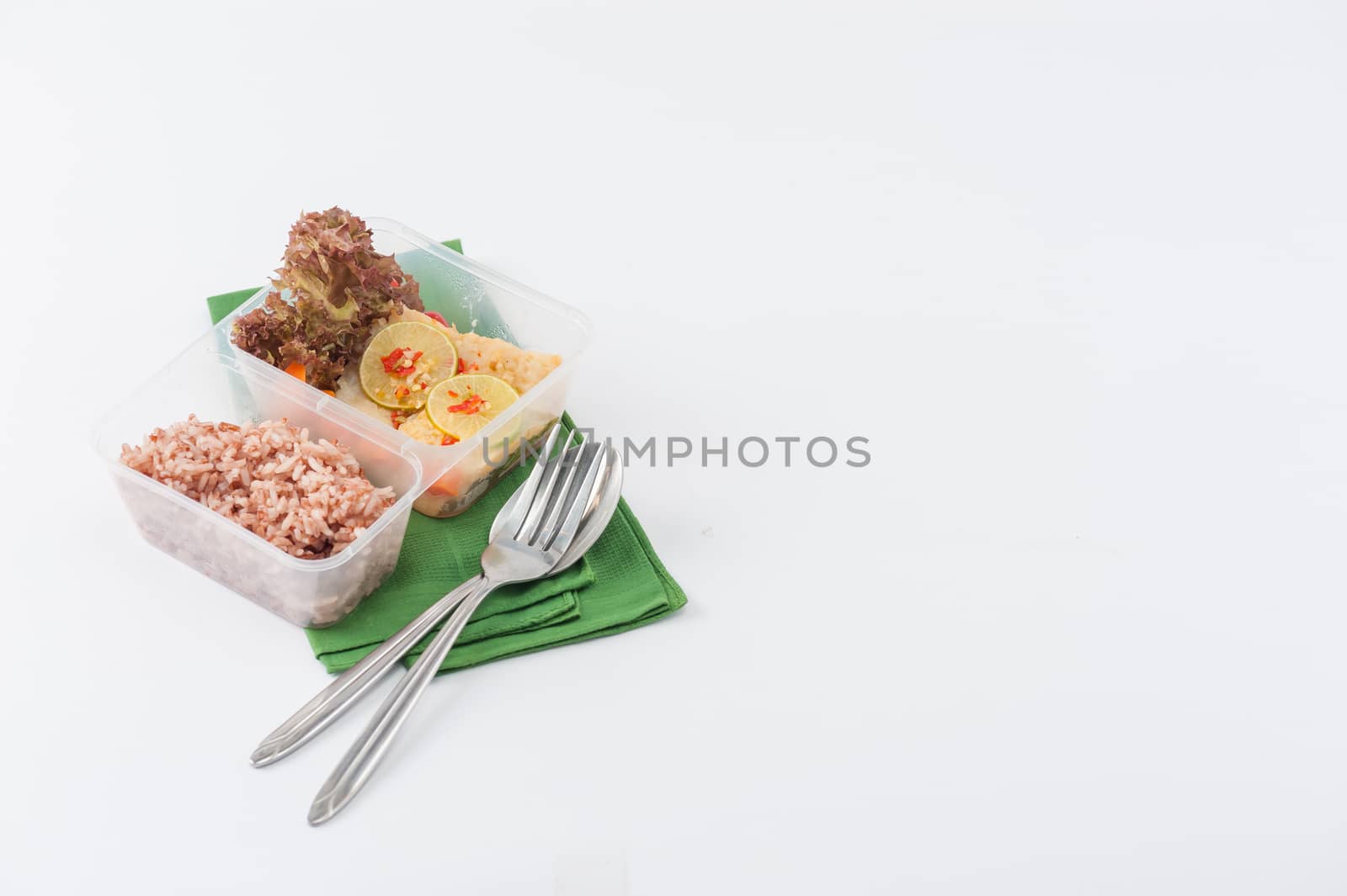 Thai style steamed fish in spicy lemon sauce cooked by clean food concept with vegetables and brown rice in lunch box on white table