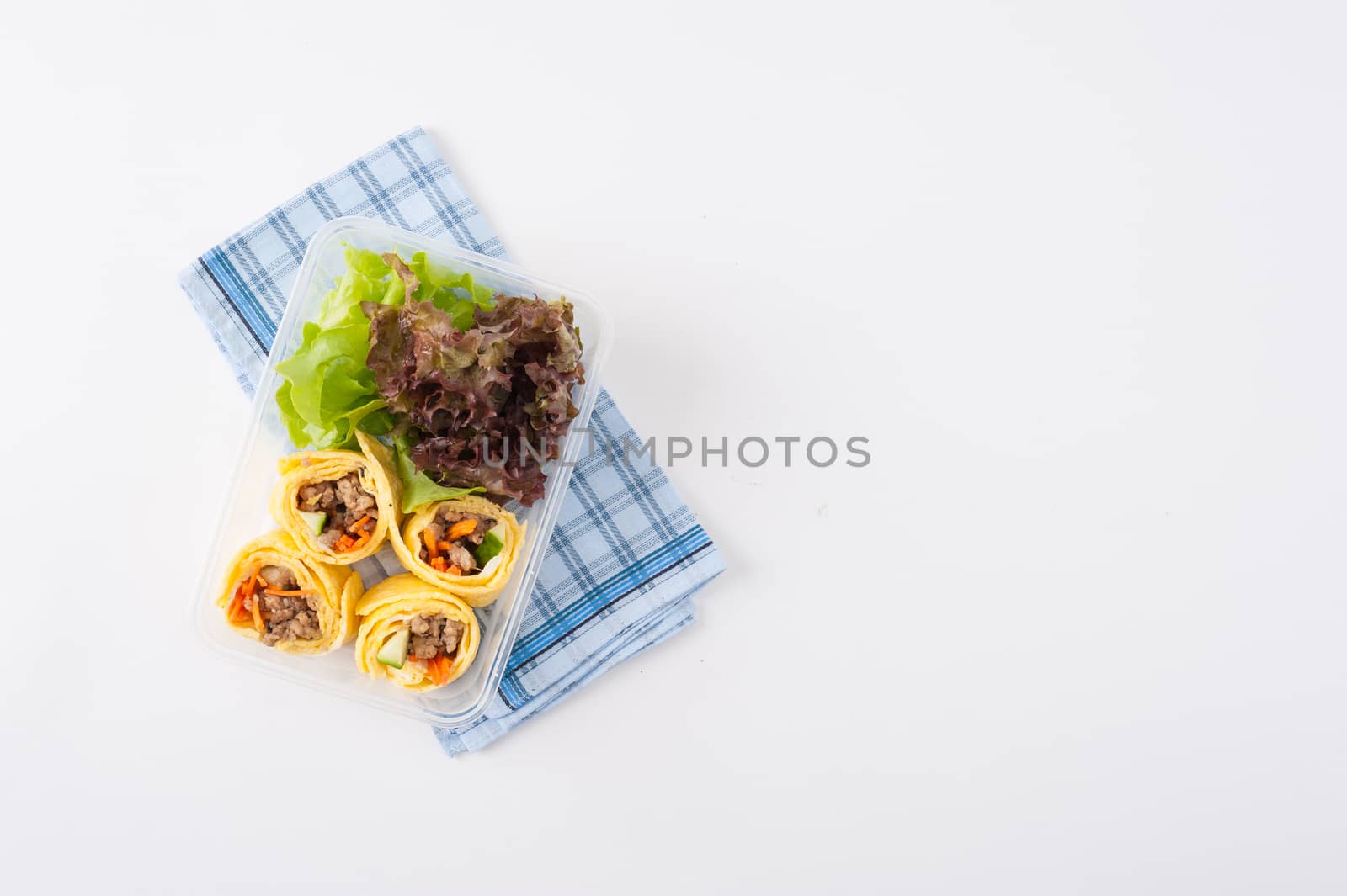 Thai spicy egg rolls (Fresh spring rolls, Kuay Teaw Lui Suan but use egg replace to rice sheet) with tofu, minced pork and vegetables cooked by clean food concept in lunch box on white table