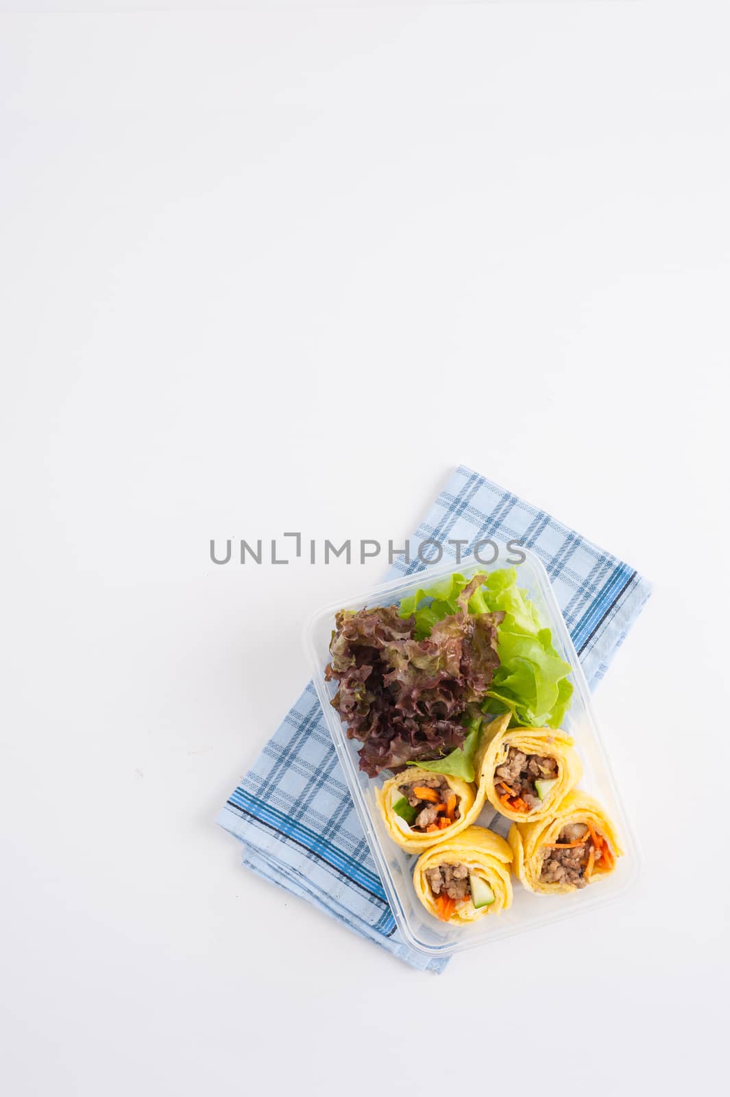 Thai spicy egg rolls (Fresh spring rolls, Kuay Teaw Lui Suan but use egg replace to rice sheet) with tofu, minced pork and vegetables cooked by clean food concept in lunch box on white table