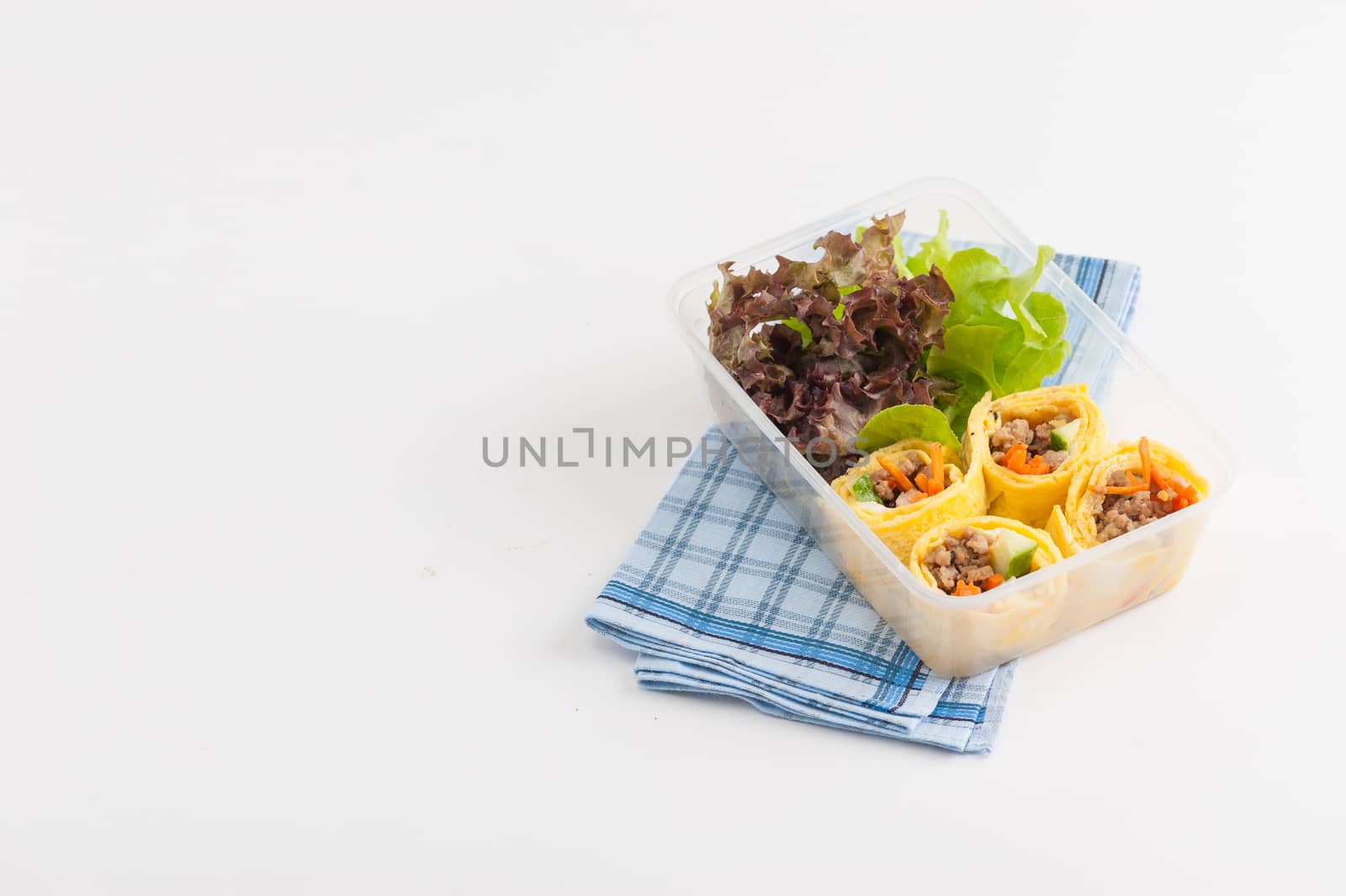 Thai spicy egg rolls (Fresh spring rolls, Kuay Teaw Lui Suan but use egg replace to rice sheet) with tofu, minced pork and vegetables cooked by clean food concept in lunch box on white table