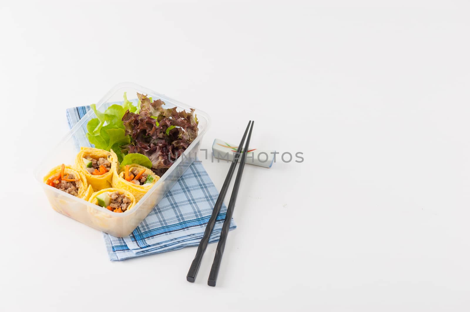 Thai spicy egg rolls (Fresh spring rolls, Kuay Teaw Lui Suan but use egg replace to rice sheet) with tofu, minced pork and vegetables cooked by clean food concept in lunch box on white table
