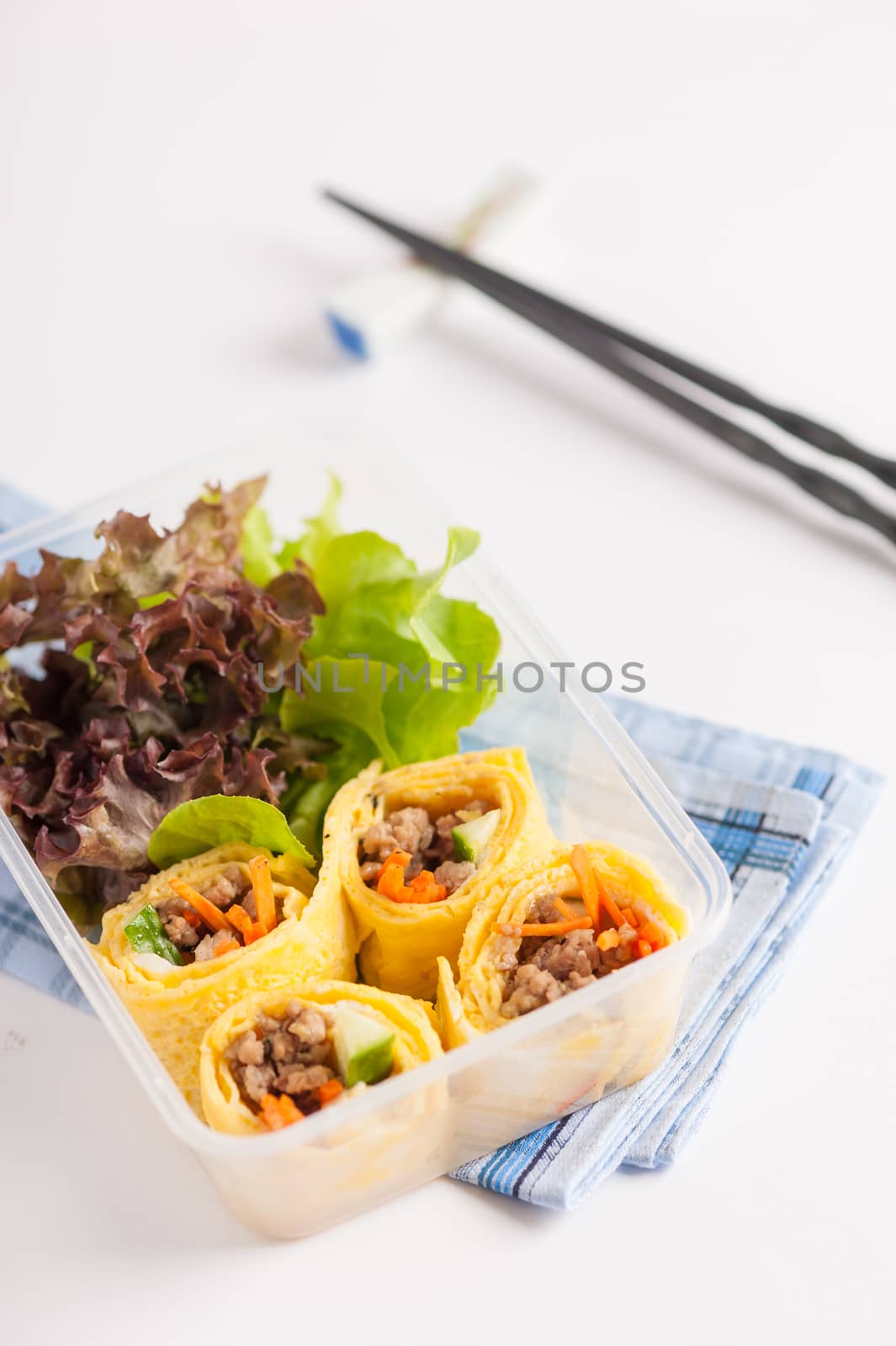 Thai spicy egg rolls (Fresh spring rolls, Kuay Teaw Lui Suan but use egg replace to rice sheet) with tofu, minced pork and vegetables cooked by clean food concept in lunch box on white table