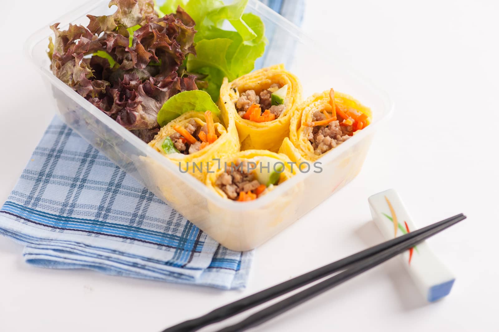 Thai spicy egg rolls (Fresh spring rolls, Kuay Teaw Lui Suan but use egg replace to rice sheet) with tofu, minced pork and vegetables cooked by clean food concept in lunch box on white table