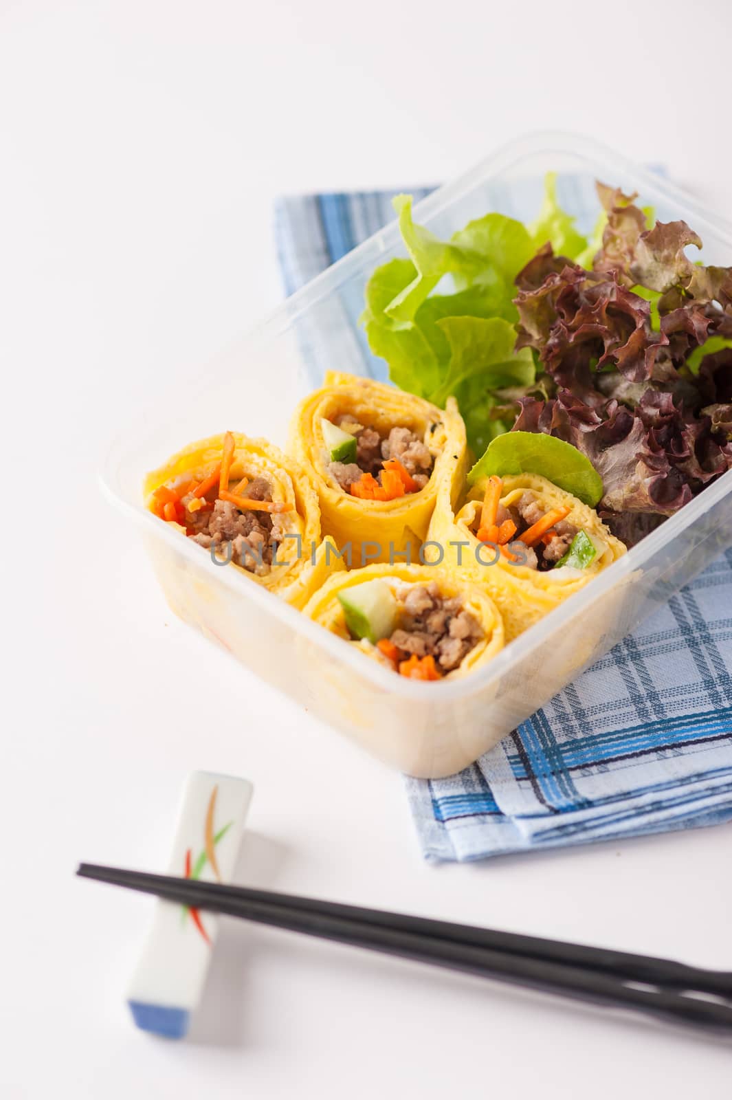 Thai spicy egg rolls (Fresh spring rolls, Kuay Teaw Lui Suan but use egg replace to rice sheet) with tofu, minced pork and vegetables cooked by clean food concept in lunch box on white table