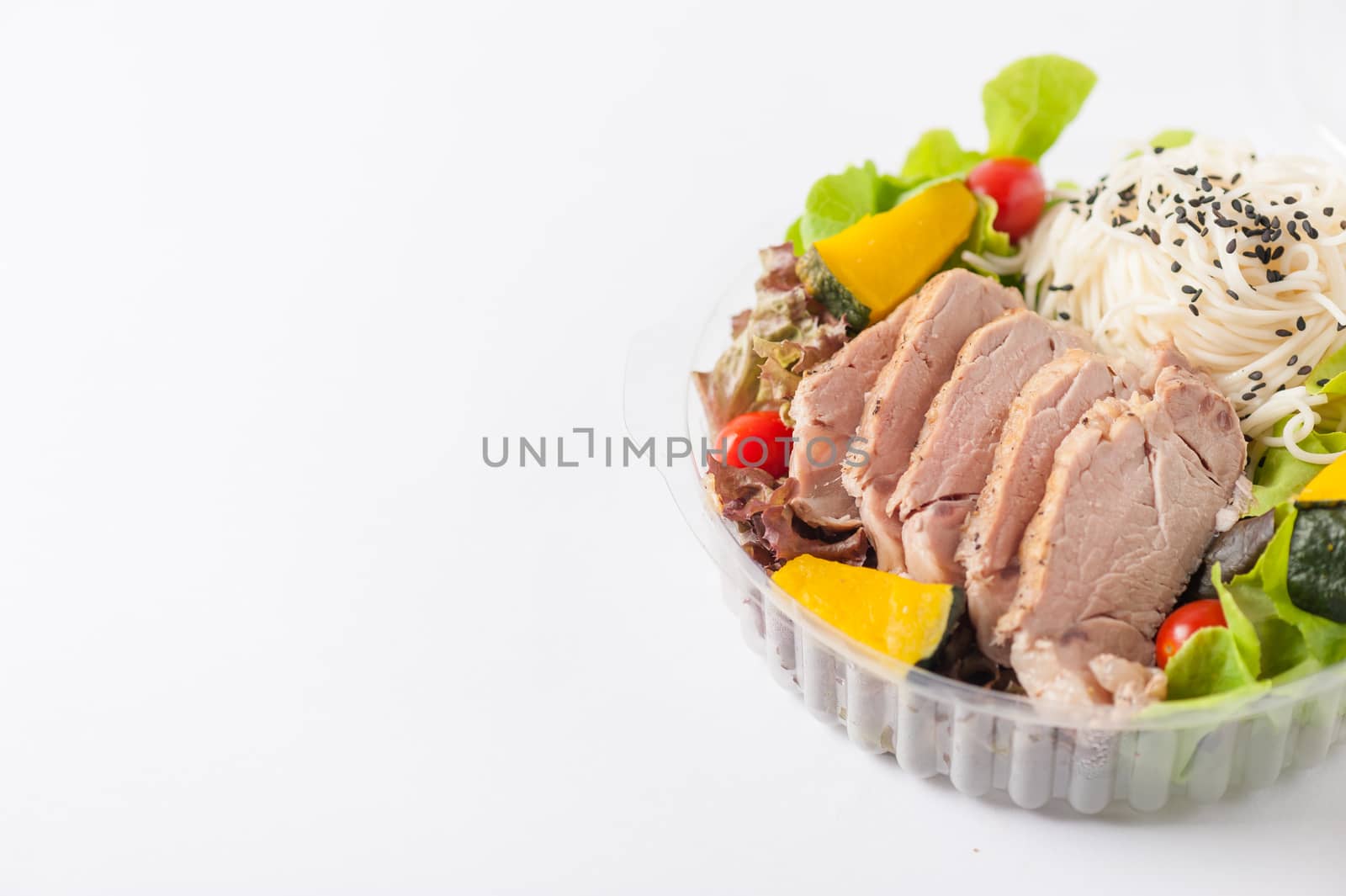 Salad with roasted pork and soba noodles by clean food concept in lunch box on white table