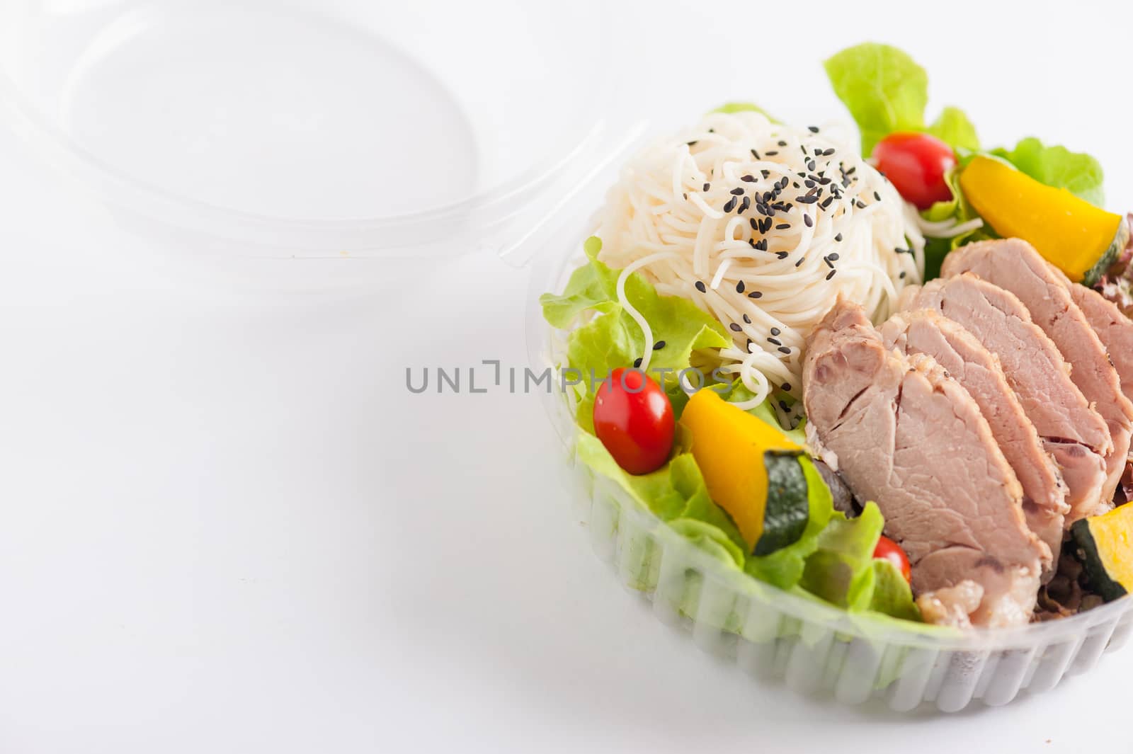 Salad with roasted pork and soba noodles by clean food concept in lunch box on white table