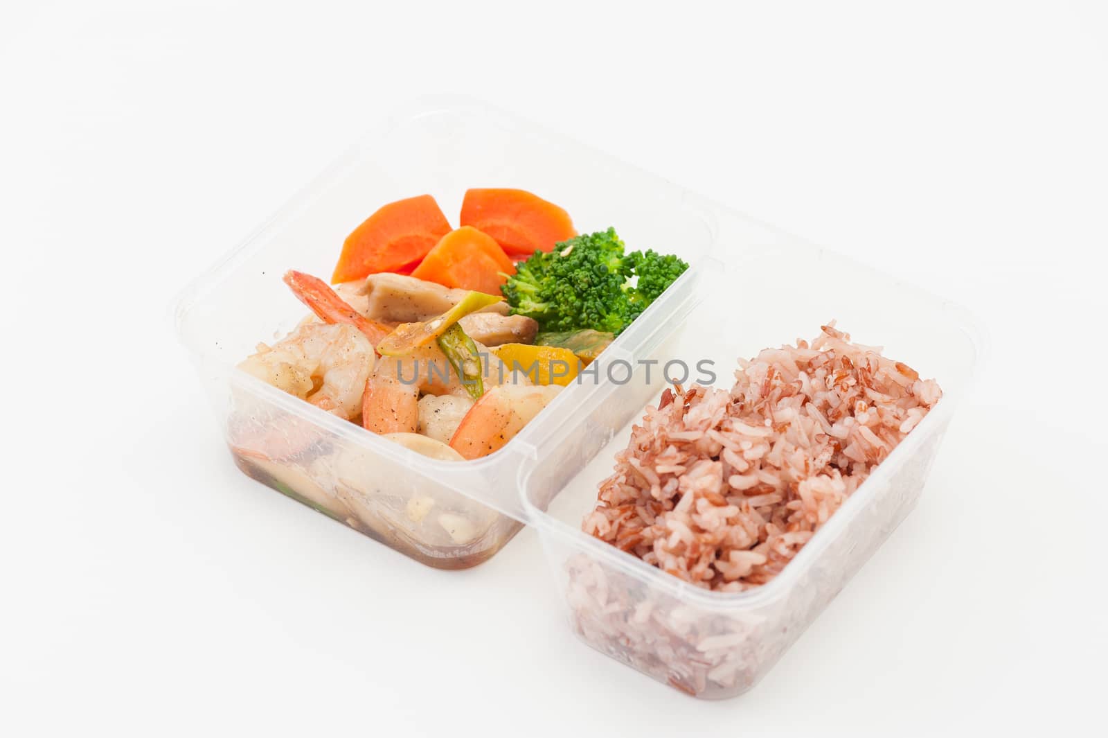 Thai style spicy stir fried shrimps cooked by clean food concept with brown rice and vegetables in lunch box on white table