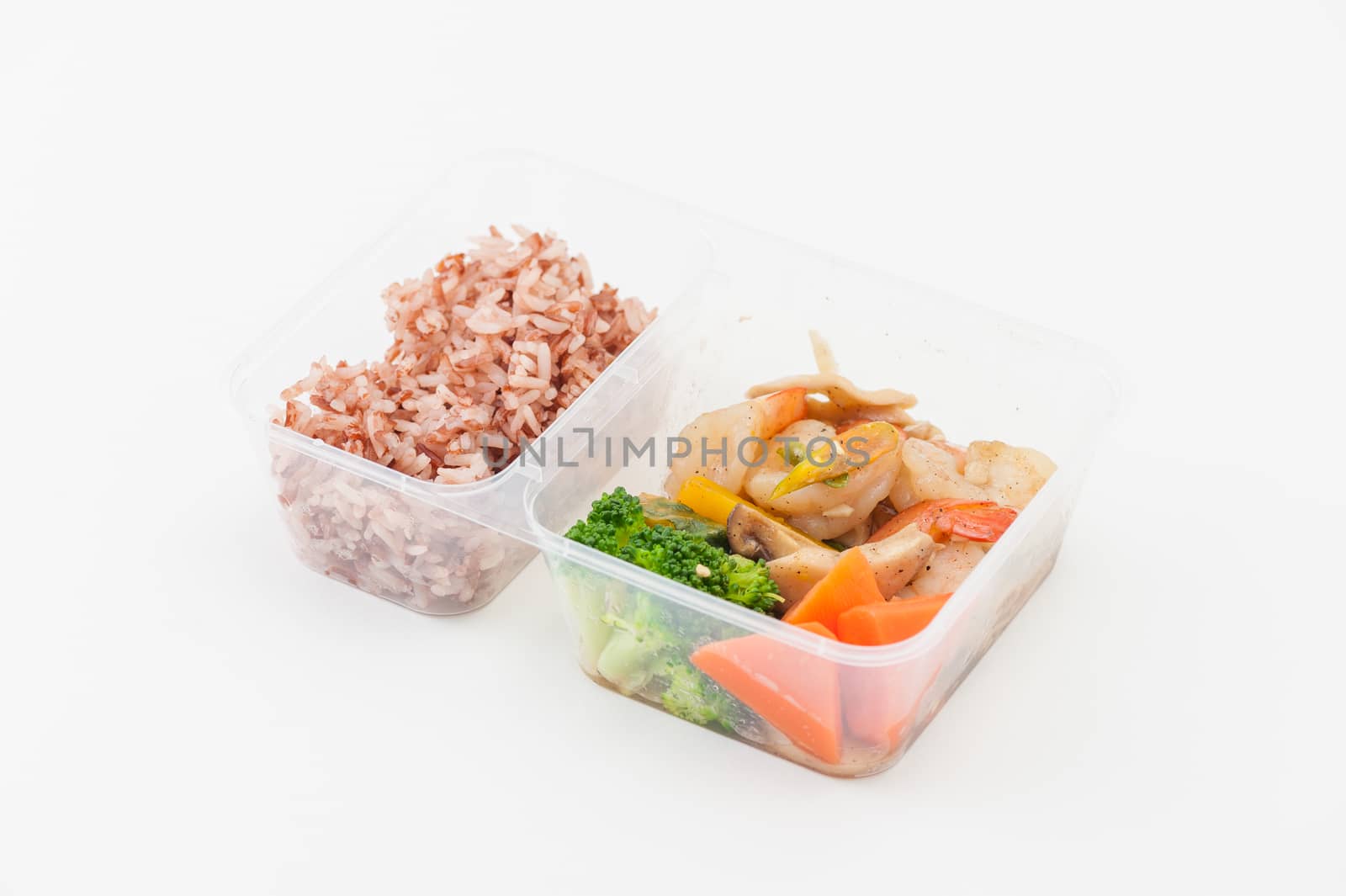 Thai style spicy stir fried shrimps cooked by clean food concept with brown rice and vegetables in lunch box on white table