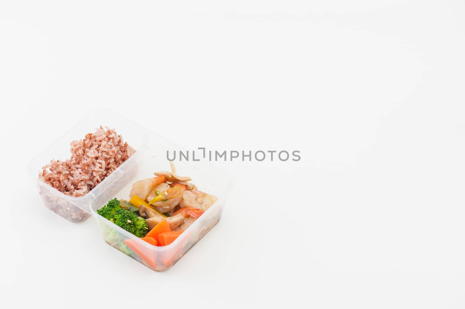 Thai style spicy stir fried shrimps cooked by clean food concept with brown rice and vegetables in lunch box on white table