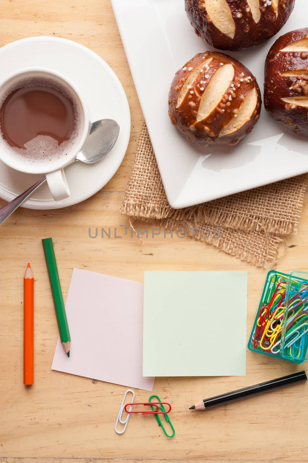 Notebook and sticky paper, paper clip, color pencil, and pen on wood table in vintage style