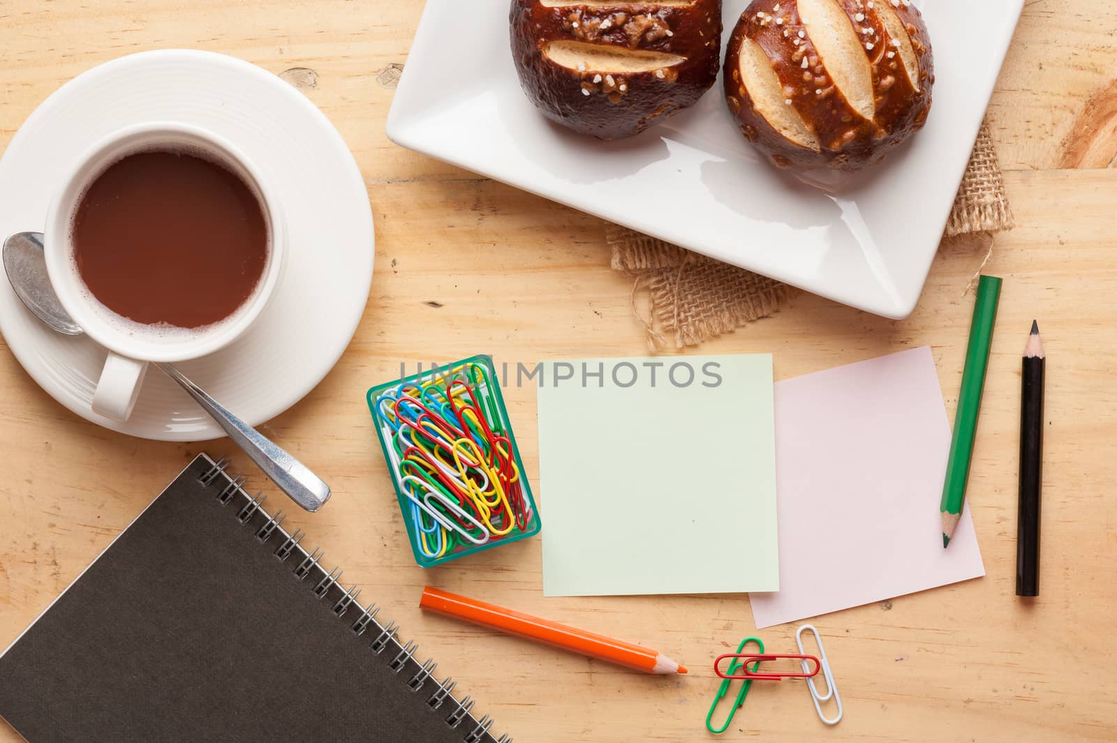 Notebook and sticky paper, paper clip, color pencil, and pen on wood table in vintage style