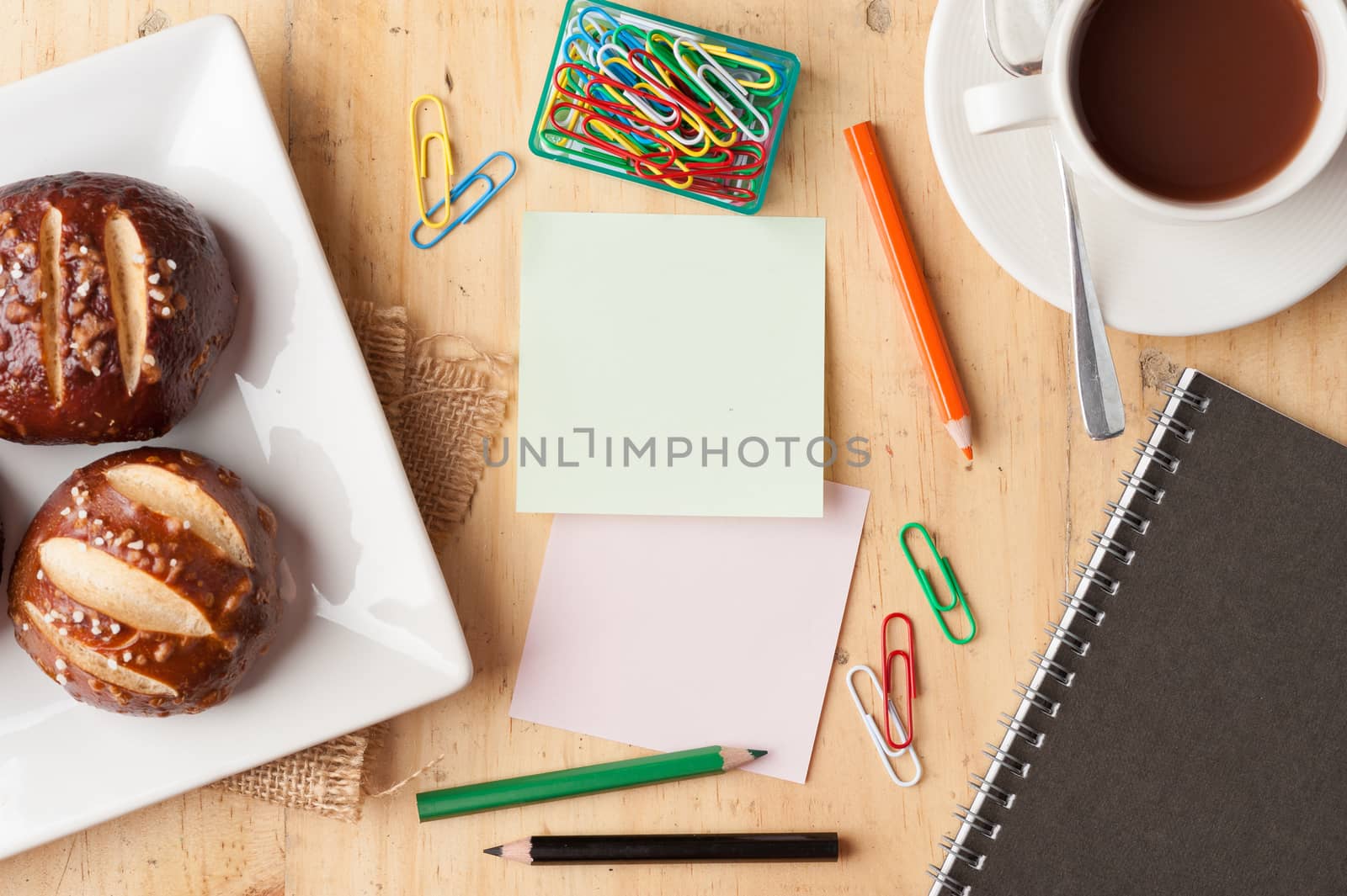 Notebook and sticky paper, paper clip, color pencil, and pen on wood table in vintage style