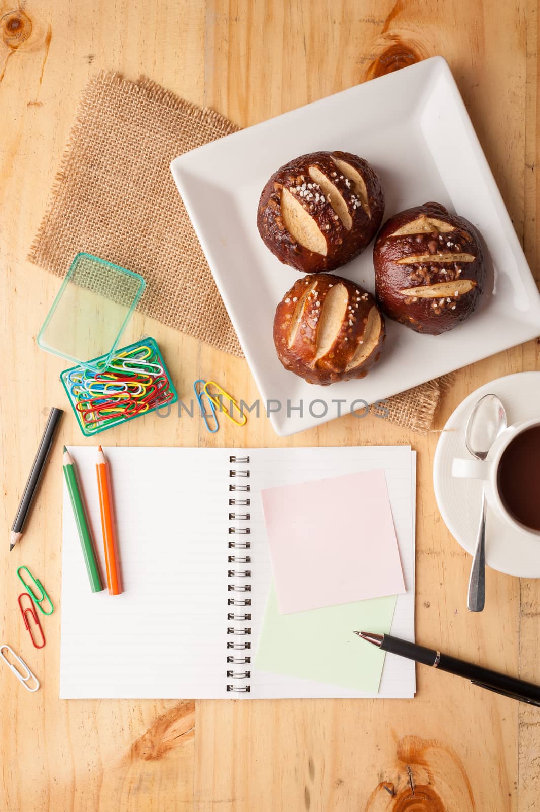 Notebook and sticky paper, paper clip, color pencil, and pen on wood table in vintage style