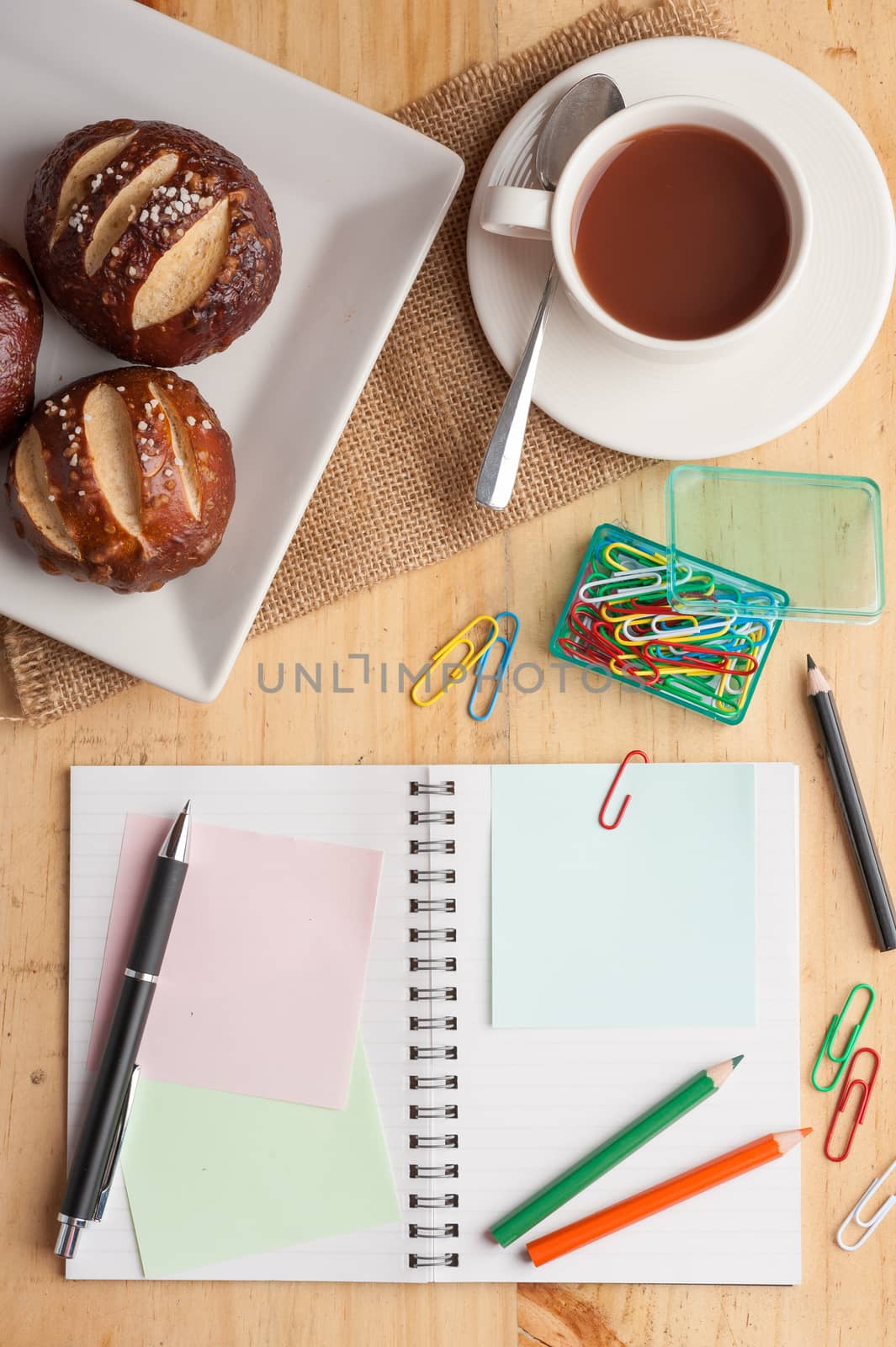 Notebook and sticky paper, paper clip, color pencil, and pen on wood table in vintage style