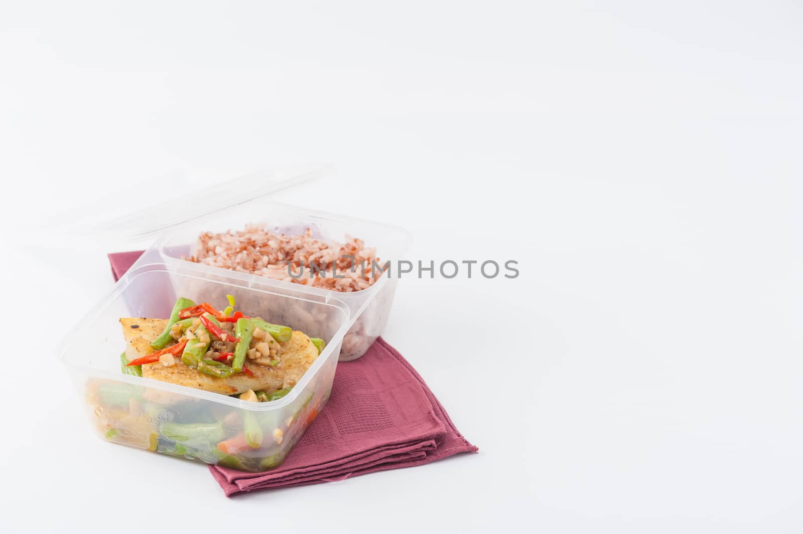 Pangasius fish fried with chili and vegetables cooked by clean food concept with brown rice in lunch box on white table
