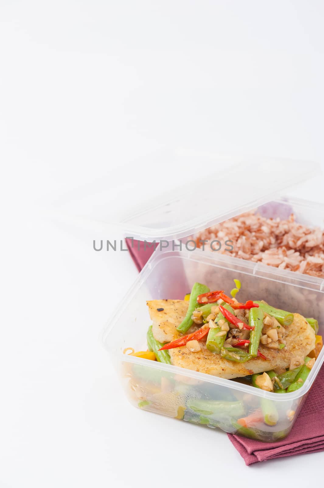 Pangasius fish fried with chili and vegetables cooked by clean food concept with brown rice in lunch box on white table