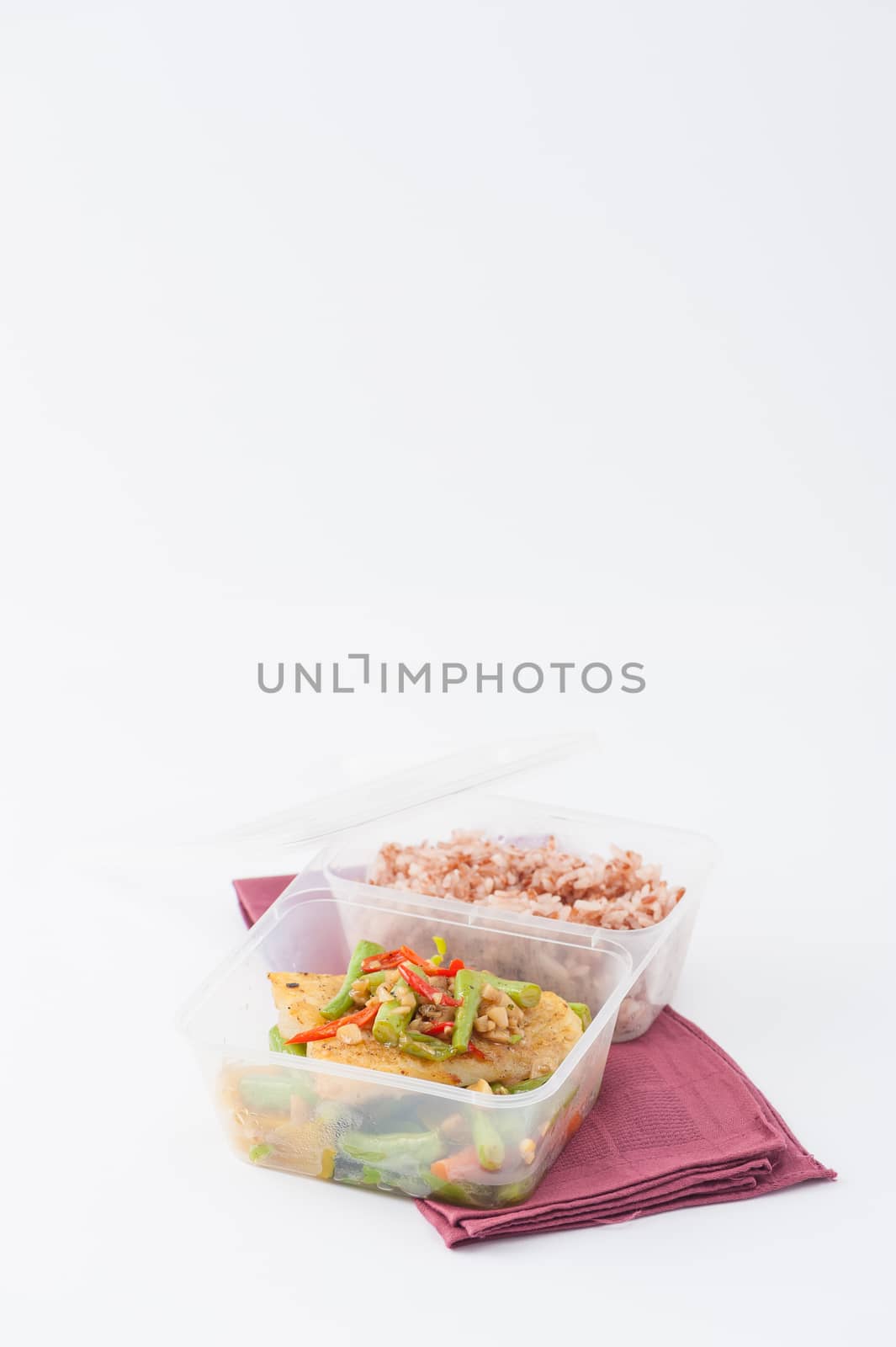 Pangasius fish fried with chili and vegetables cooked by clean food concept with brown rice in lunch box on white table