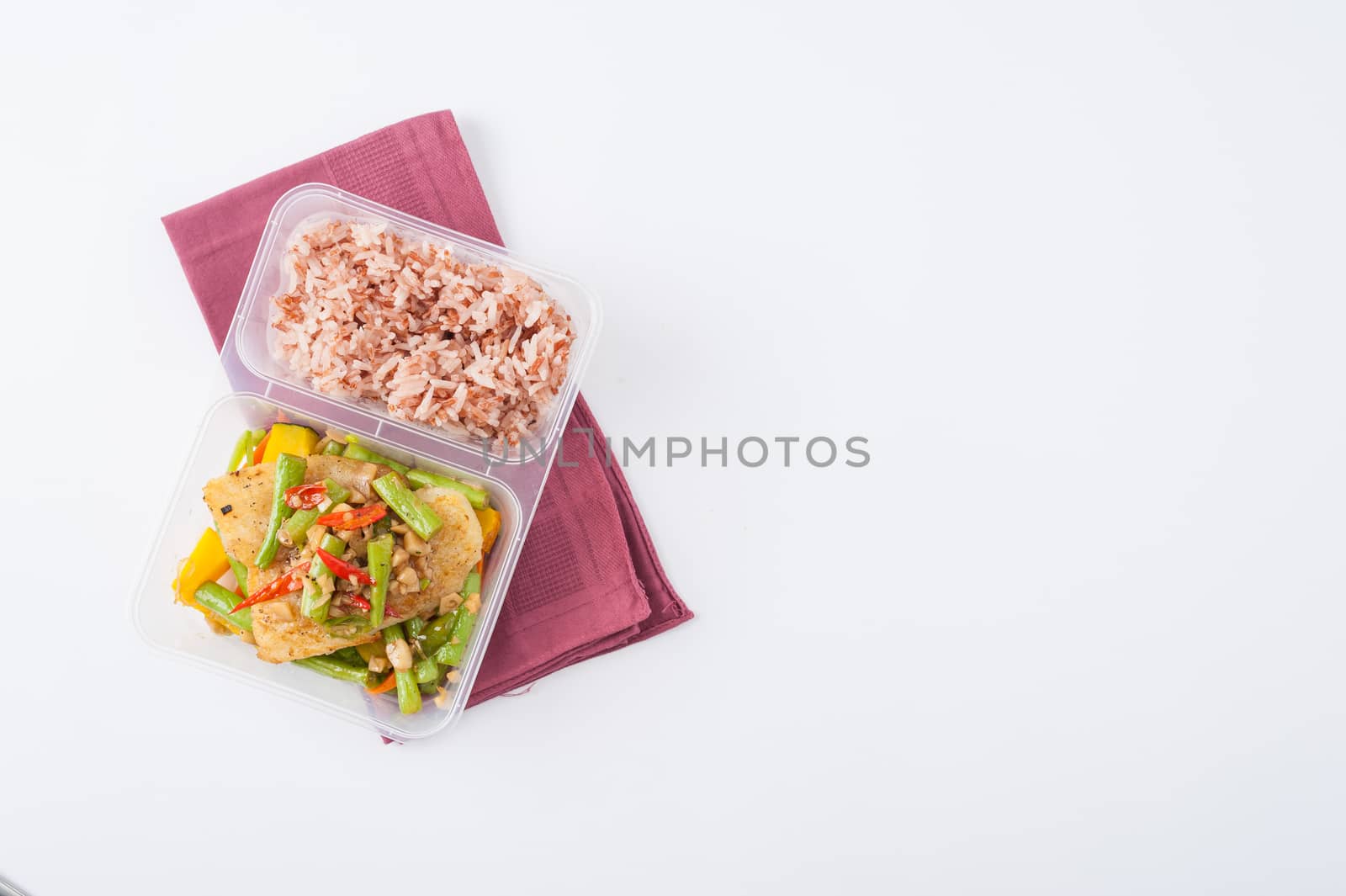 Pangasius fish fried with chili and vegetables cooked by clean food concept with brown rice in lunch box on white table
