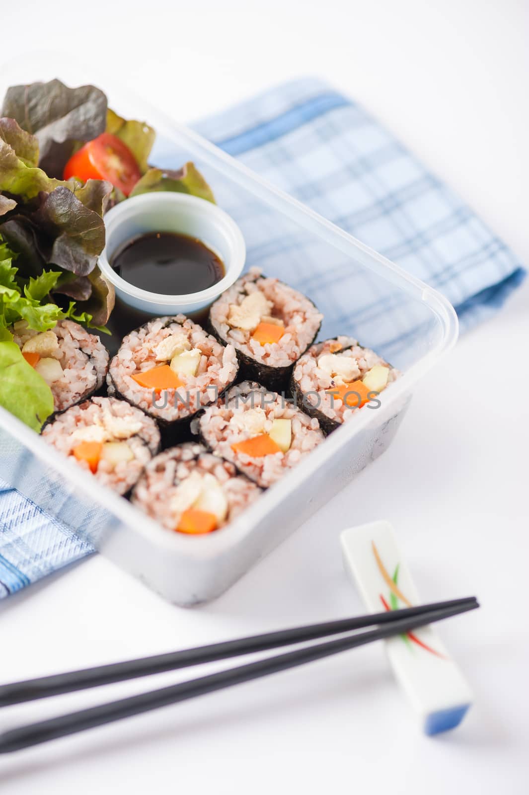 Japanese style brown rice maki with grilled chicken, grilled pork, and grilled tofu cooked by clean food concept in lunch box on white table
