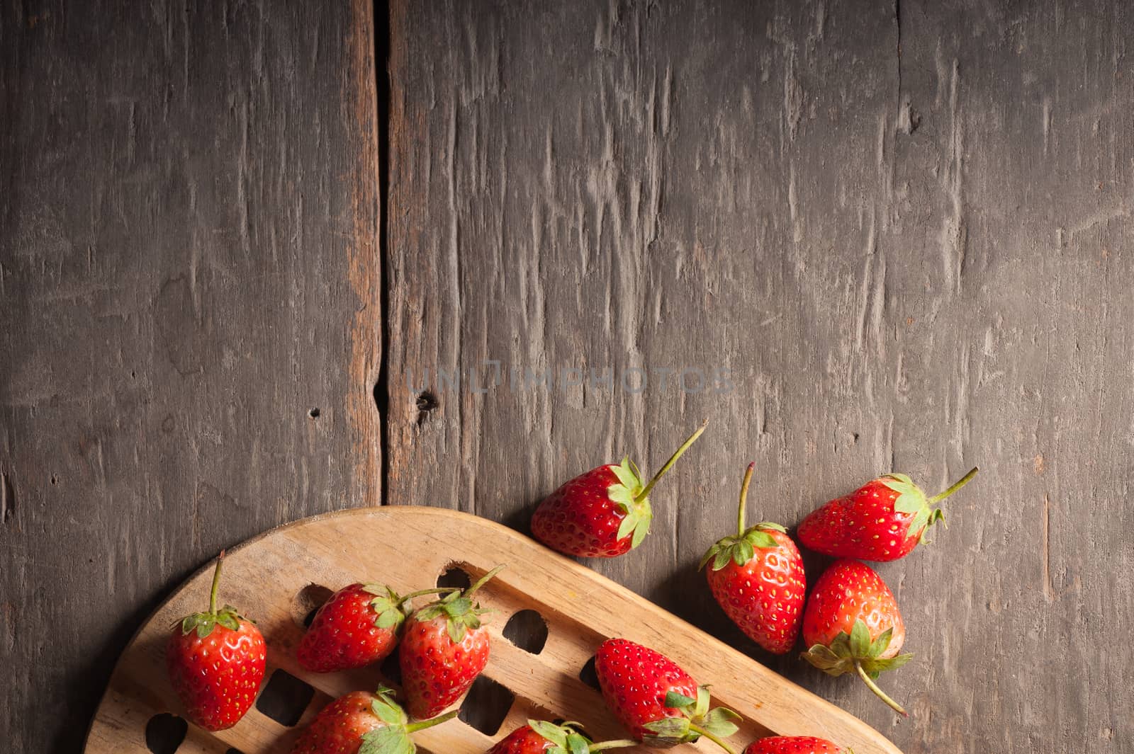Strawberries on wood background in vintage style with low key scene.