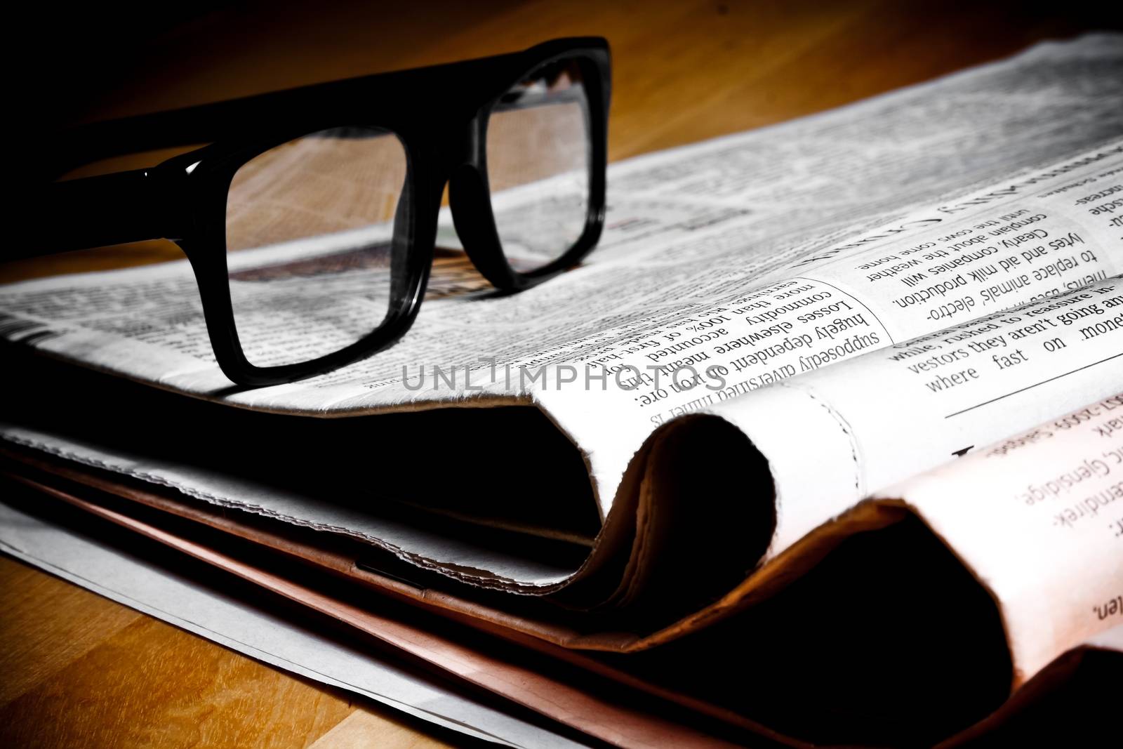 glasses on stack of newspapers on wood table