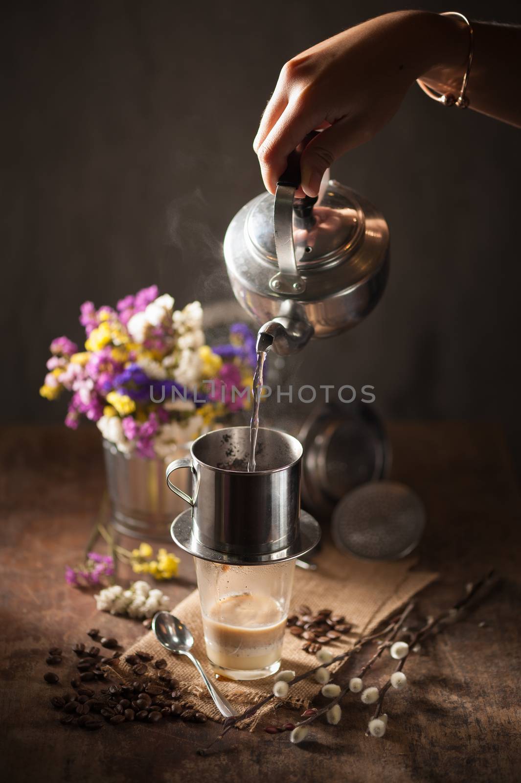 Vietnamese style drip coffee, Woman hand pouring hot water into metal coffee filter with low key scene