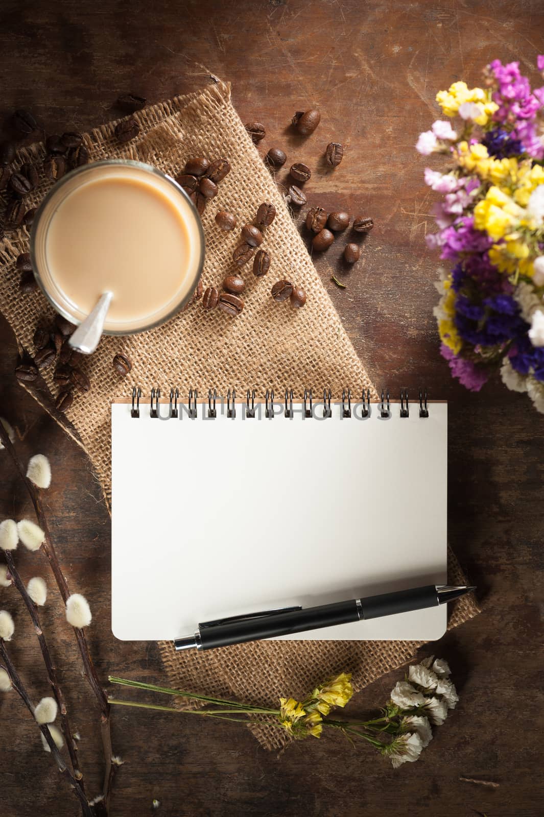 Notepad with pen, a glass of Thai tea and bits of red velvet cake on rustic wood background with low key scene