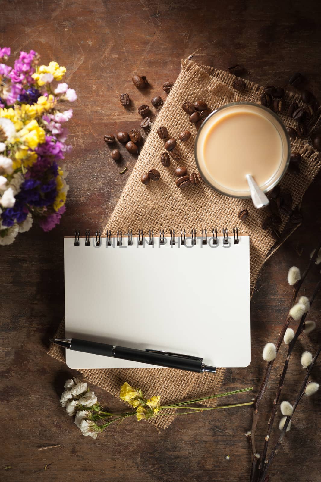 Notepad with pen, a glass of Thai tea and bits of red velvet cake on rustic wood background with low key scene