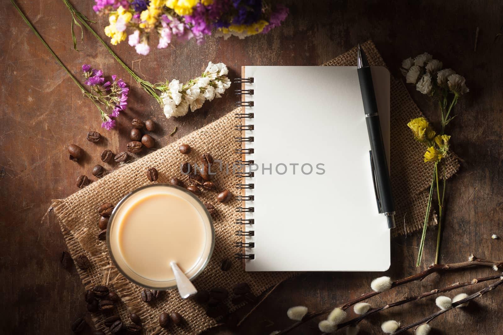 Notepad with pen, a glass of Thai tea and bits of red velvet cake on rustic wood background with low key scene