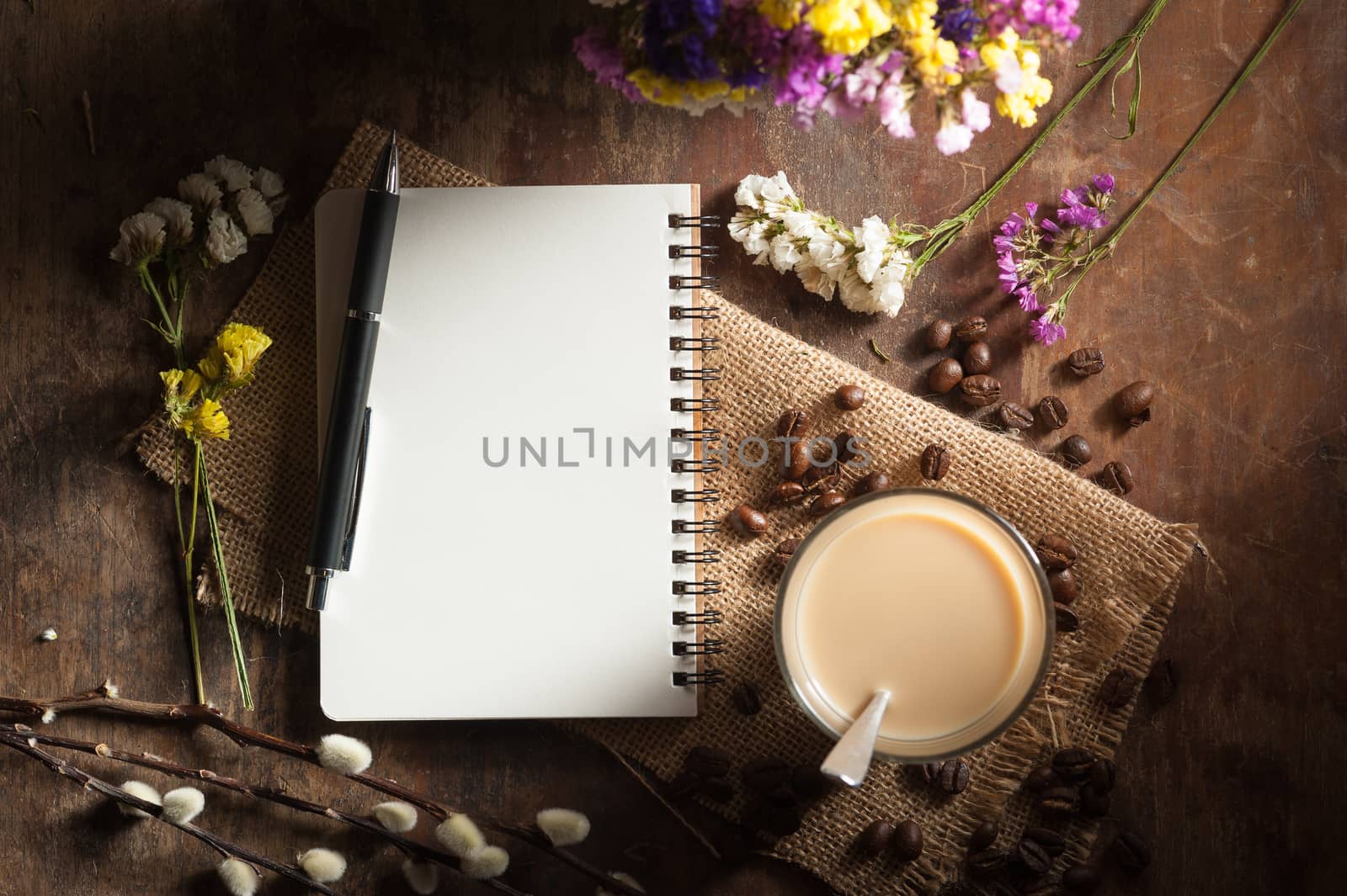Notepad with pen, a glass of Thai tea and bits of red velvet cake on rustic wood background with low key scene