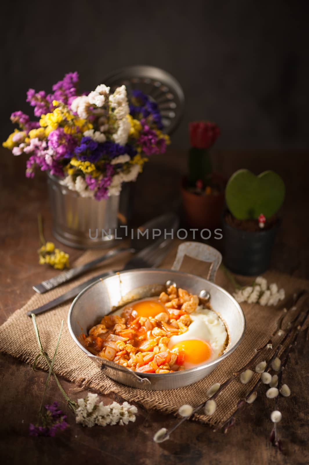 Vietnamese style fried egg in metal pan with white pork and onion on wood table in vintage style with low key scene