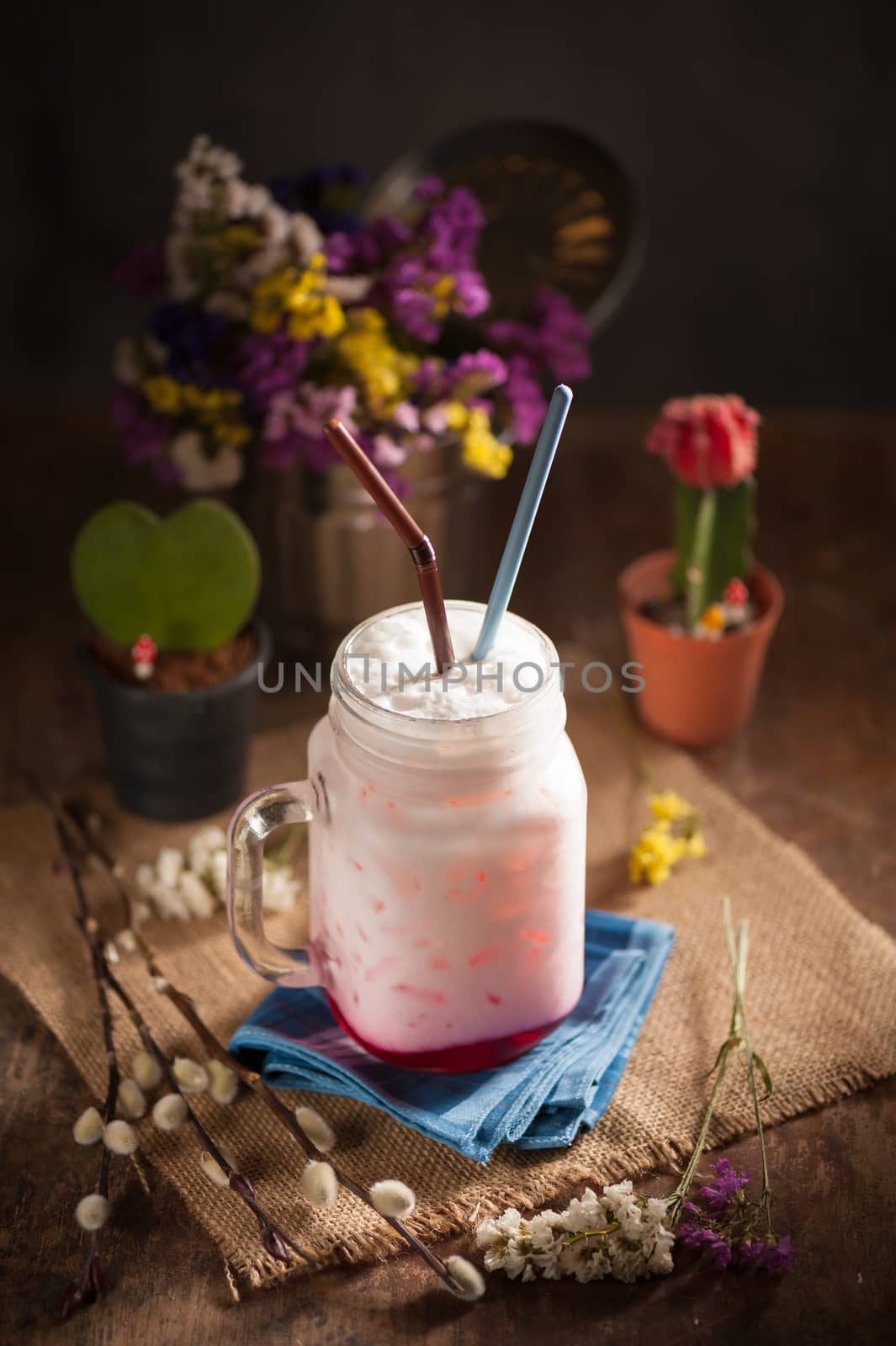 Fresh milk with red syrup on wood table in cafe with low key scene