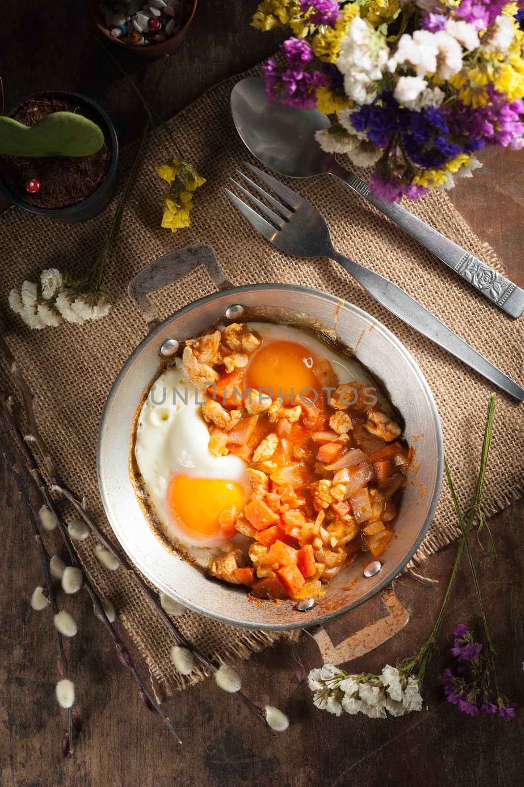 Vietnamese style fried egg in metal pan with white pork and onion on wood table in vintage style with low key scene