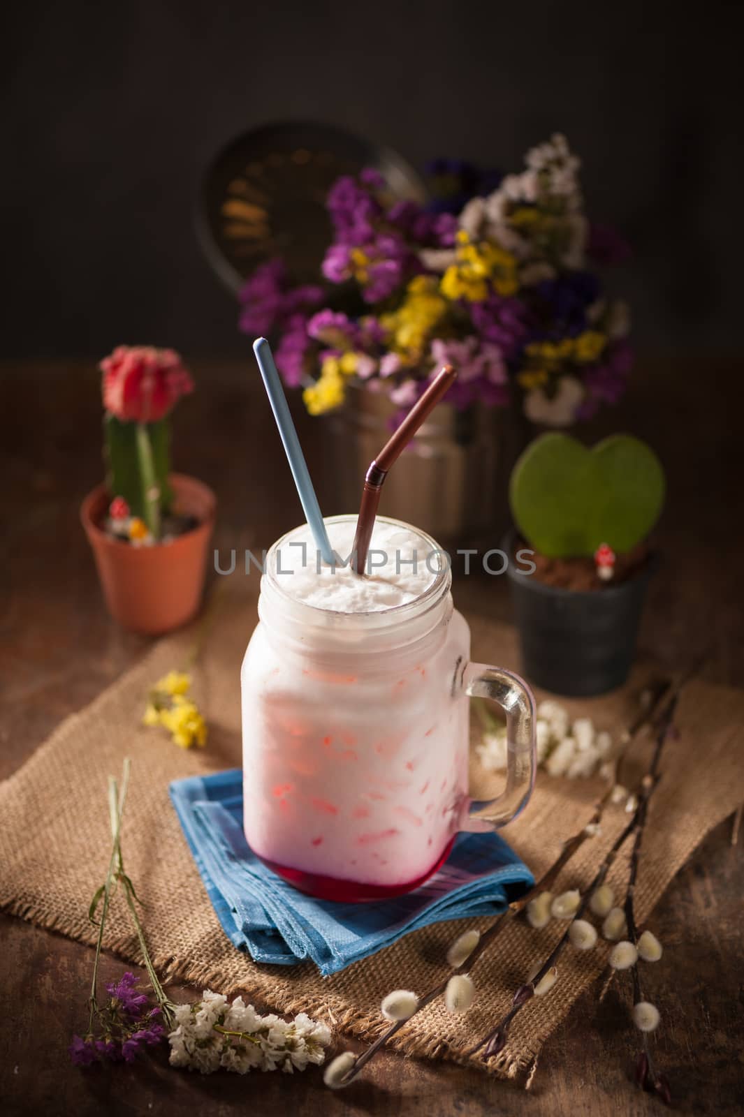 Fresh milk with red syrup on wood table in cafe with low key scene