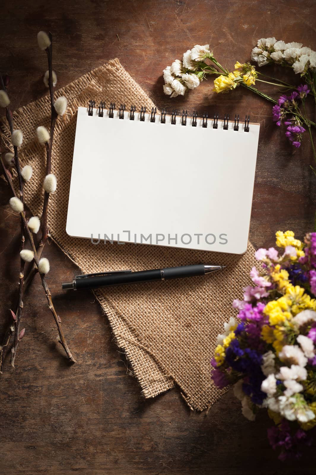 Small notepad with pen and pencil on rustic wood background with film filter effect