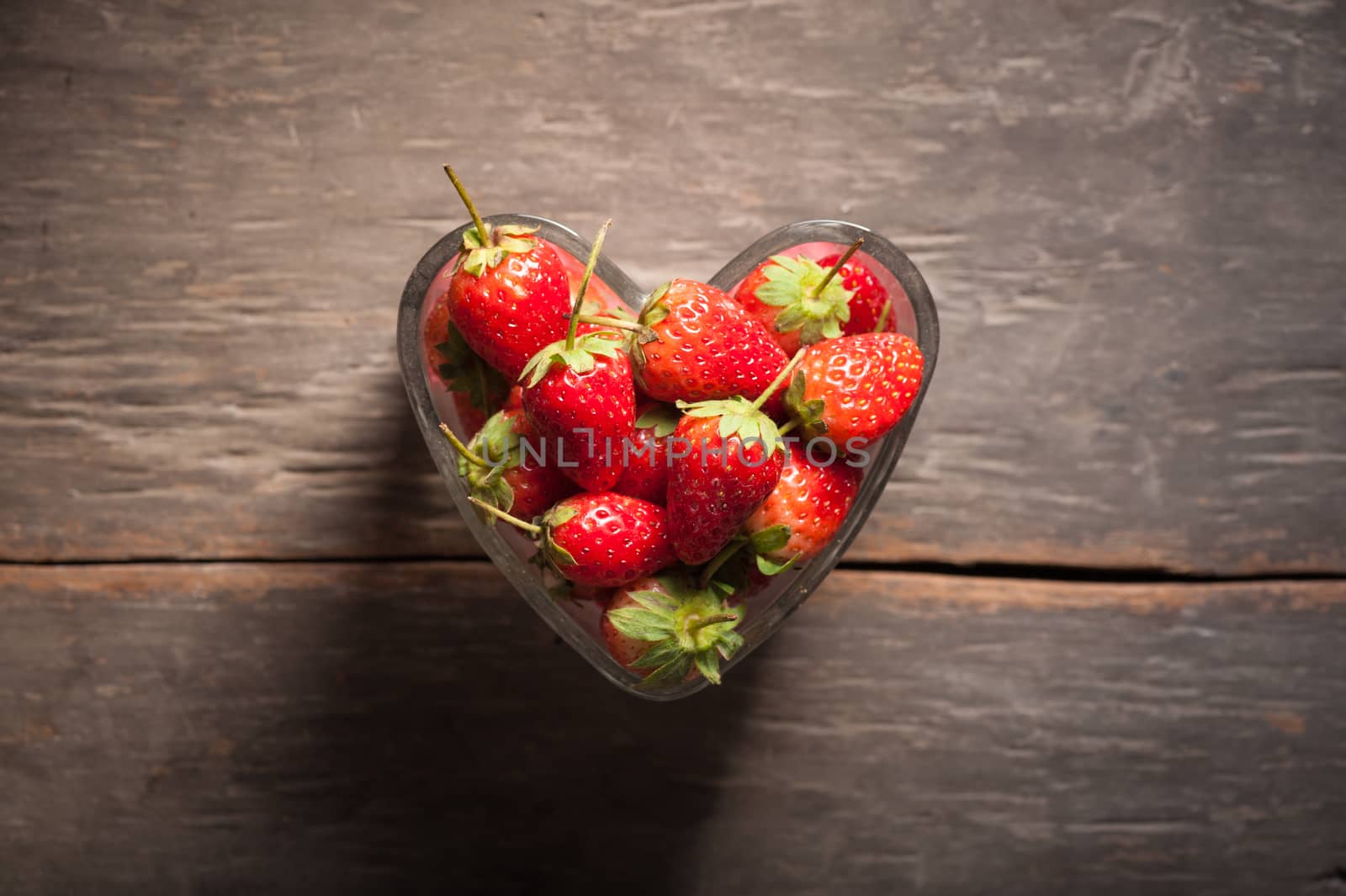 Strawberries on wood background in vintage style with low key scene.