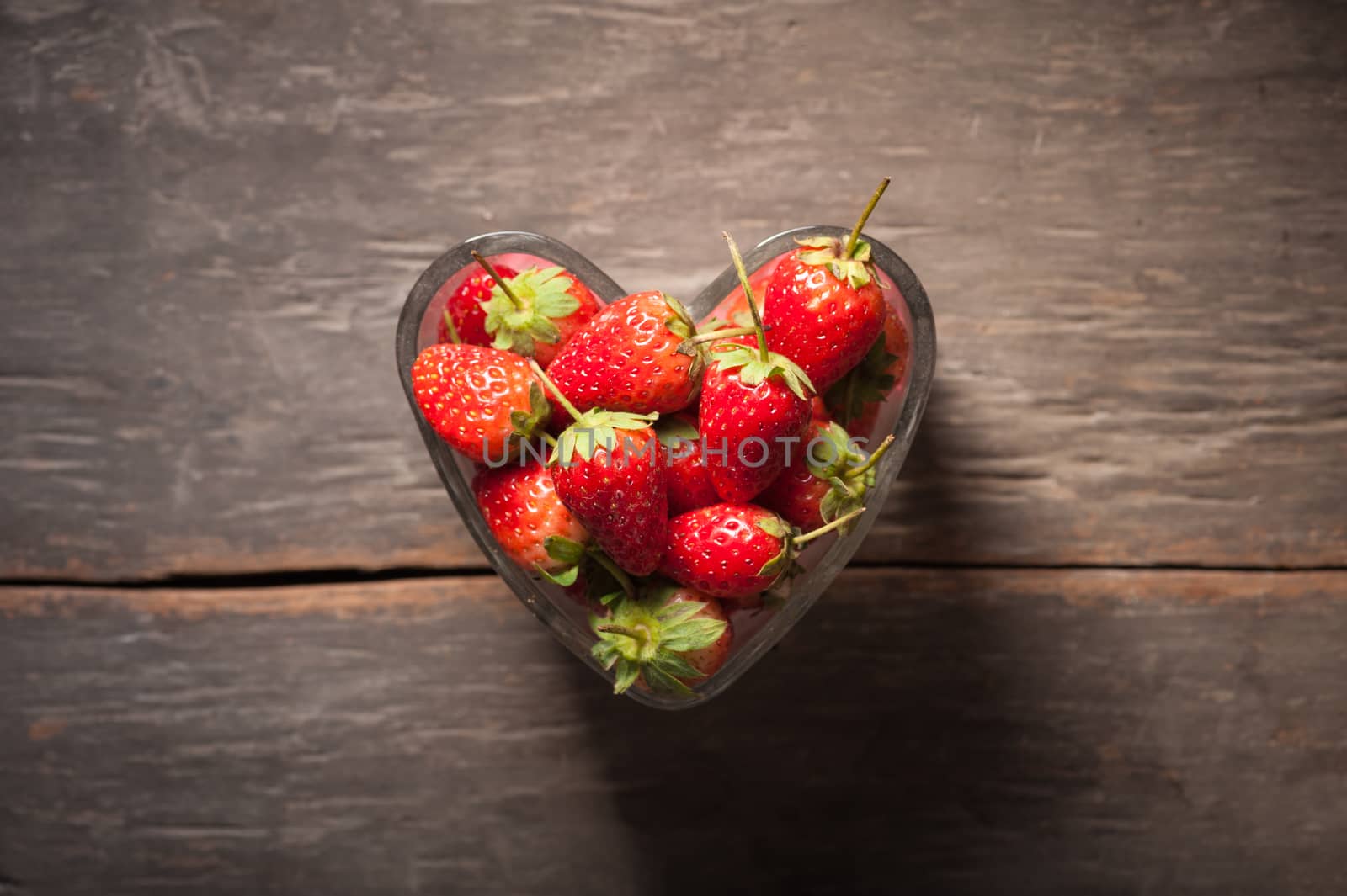 Strawberries on wood background in vintage style with low key scene.