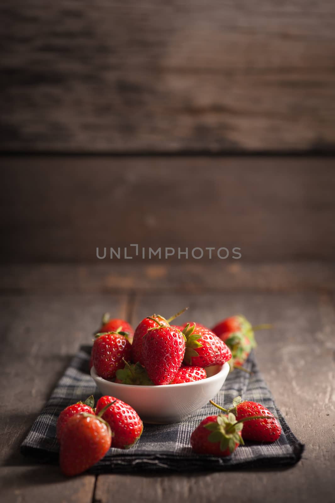 Strawberries on wood background in vintage style with low key scene.