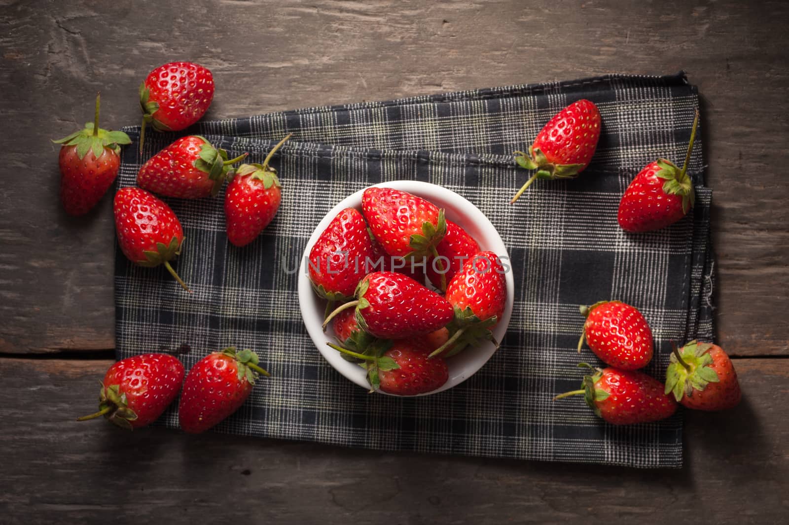 Strawberries on wood background in vintage style with low key scene.