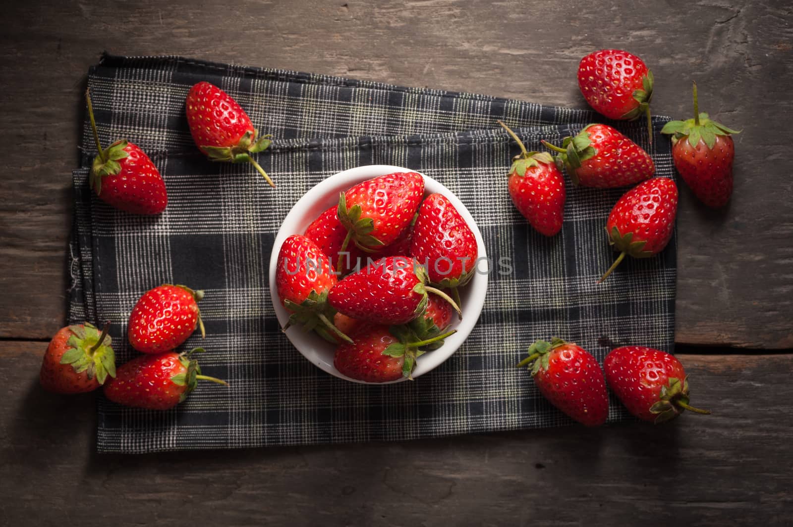 Strawberries on wood background in vintage style with low key scene.